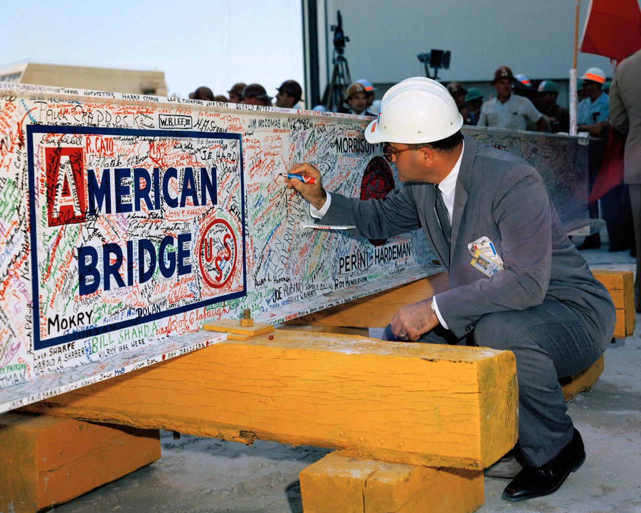 Colonel Rocco Patrone (Director, Plans, Programs and Resources Office NASA-KSC) signs the last major beam also autographed by construction workers, NASA, and Corps of Engineers employees  to be installed during the VAB Topping-Off Ceremony. MILA.