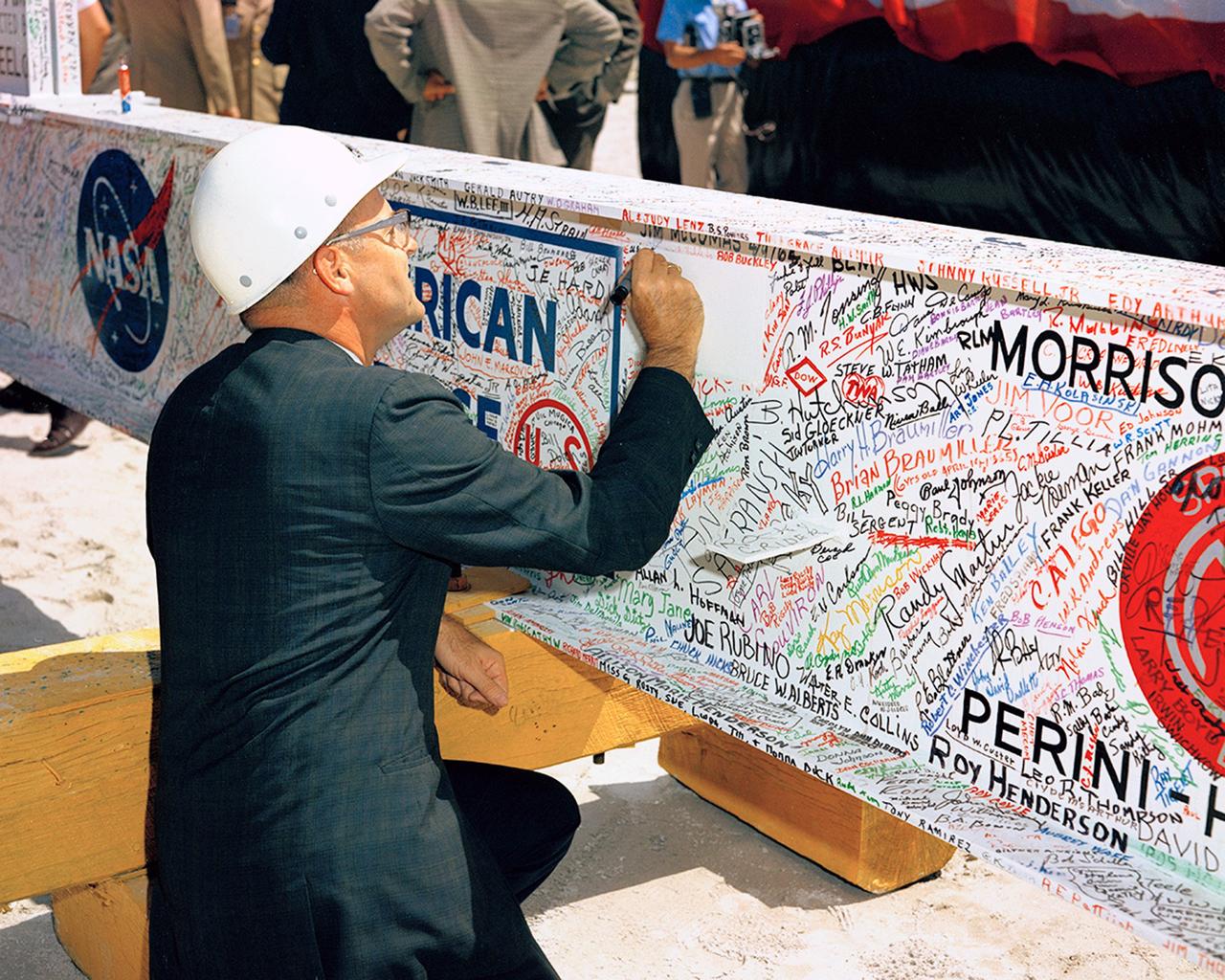CAPE CANAVERAL, Fla. -- Mr. A. Siepert, assistant director, NASA-KSC, signs the last major beam autographed by construction workers, NASA, and Corps of Engineers employees to be installed during the VAB Topping-Off Ceremony. MILA. Photo credit: NASA