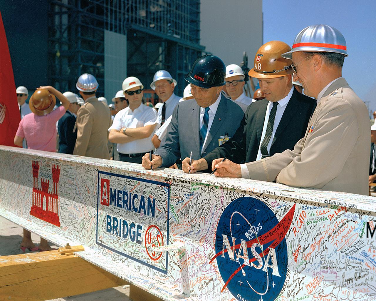 Dr. Kurt Debus (Director, NASA-KSC) signs the last major beam autographed by construction workers, NASA, and Corps of Engineers employees to be installed during the VAB Topping-Off Ceremony. MILA.