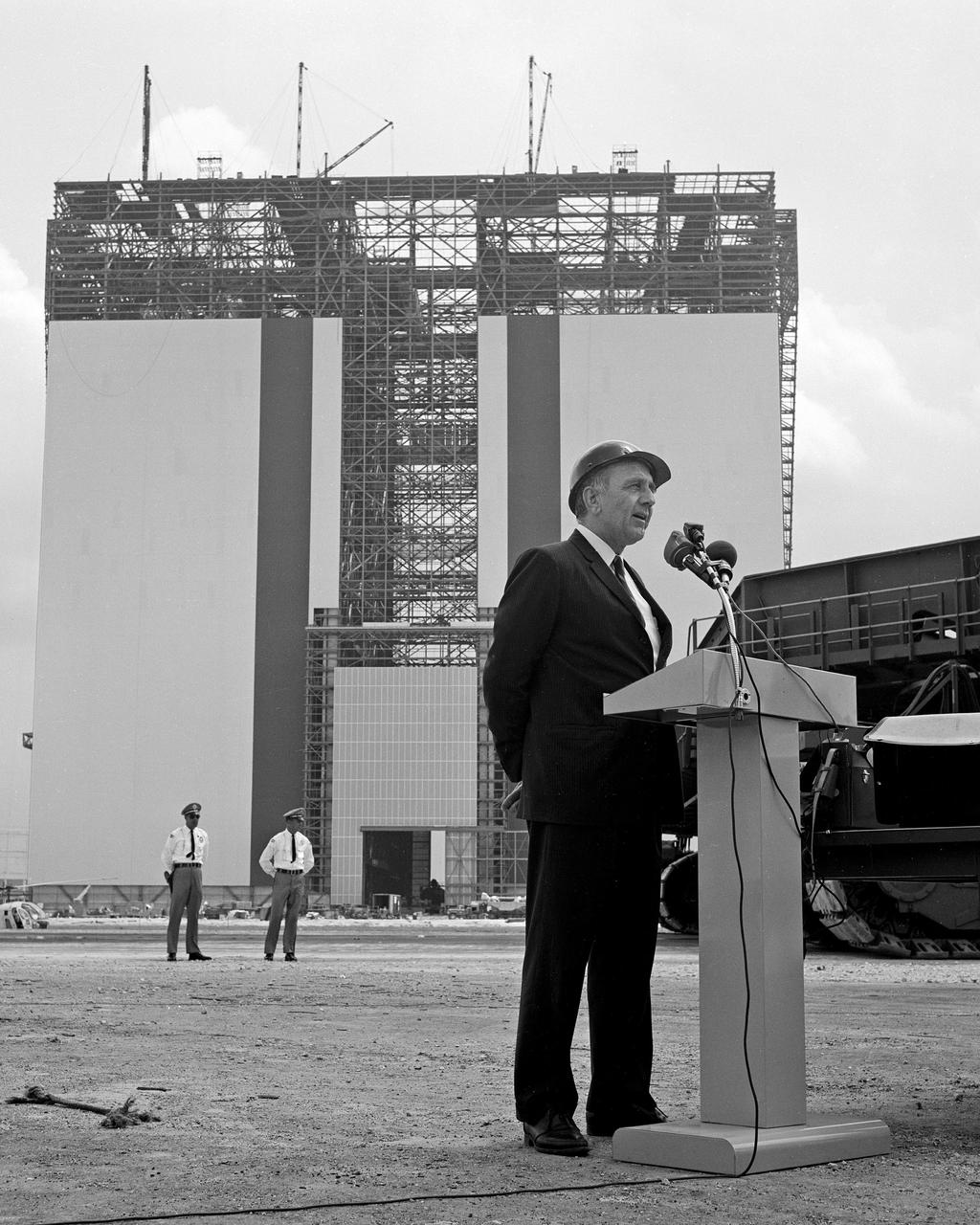 CAPE KENNEDY, Fla. -- At the Kennedy Space Center in Florida, Dr. Kurt H. Debus, center director, speaks at the "topping off" ceremonies for the Vehicle Assembly Building. A crawler-transporter is seen at the right. One of the largest buildings in the world, the 129 million cubic foot structure will be used to prepare the Apollo Saturn V launch vehicles for missions to land astronauts on the moon. Photo Credit: NASA