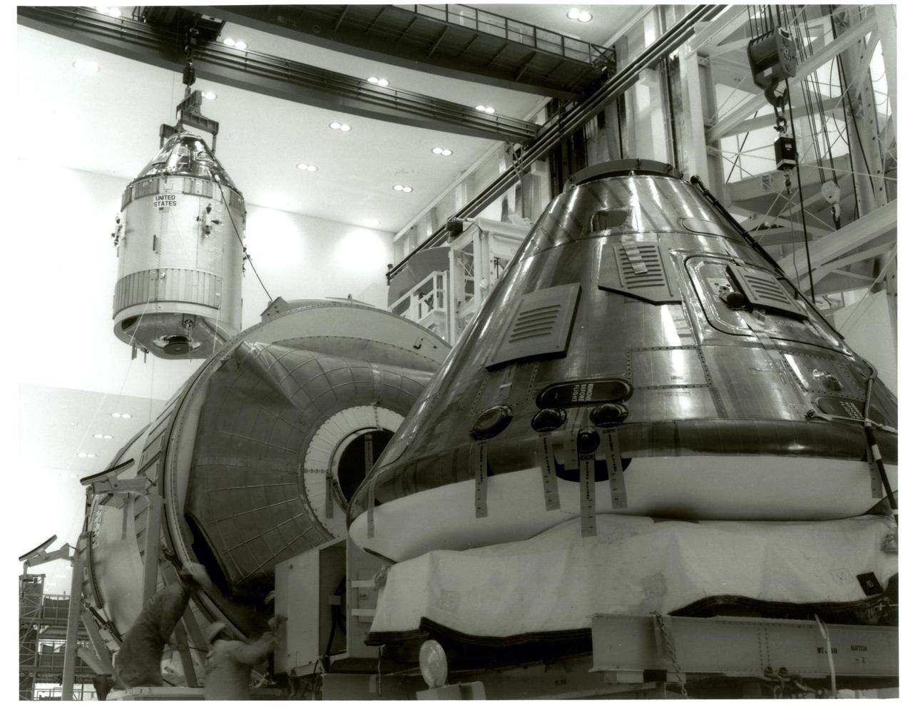 KENNEDY SPACE CENTER, FLA.  - The Command Module 107 and Service Module, which are going to be used for the Apollo 11 mission, are moved from Chamber "L" to the work stand in preparation for the first manned lunar landing.  Also shown in the background is the Command Module 108, which is going to be used for the Apollo 12 lunar landing mission.