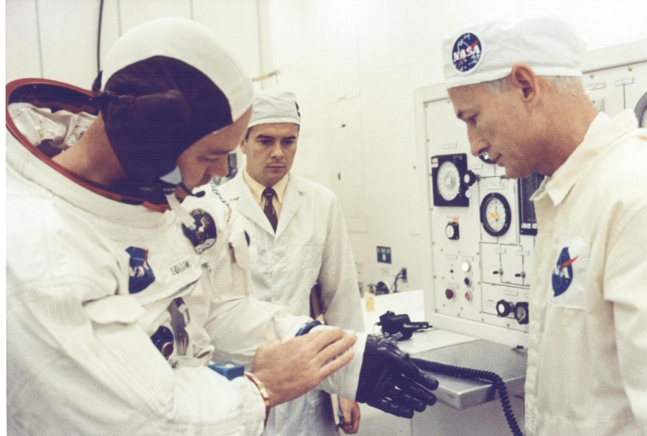 KENNEDY SPACE CENTER, FLA. - Apollo 11 Command Module Pilot Michael Collins appears to be explaining a point about his spacesuit glove to technician Joe Schmitt during suiting operations in the Manned Spacecraft Operations Building prior to the astronauts' departure to Launch Pad 39A.  The three astronauts, Edwin E. Aldrin Jr., Neil A. Armstrong and Michael Collins will then board the Saturn V launch vehicle, scheduled for a 9:32 a.m. EDT liftoff for the first manned lunar landing.