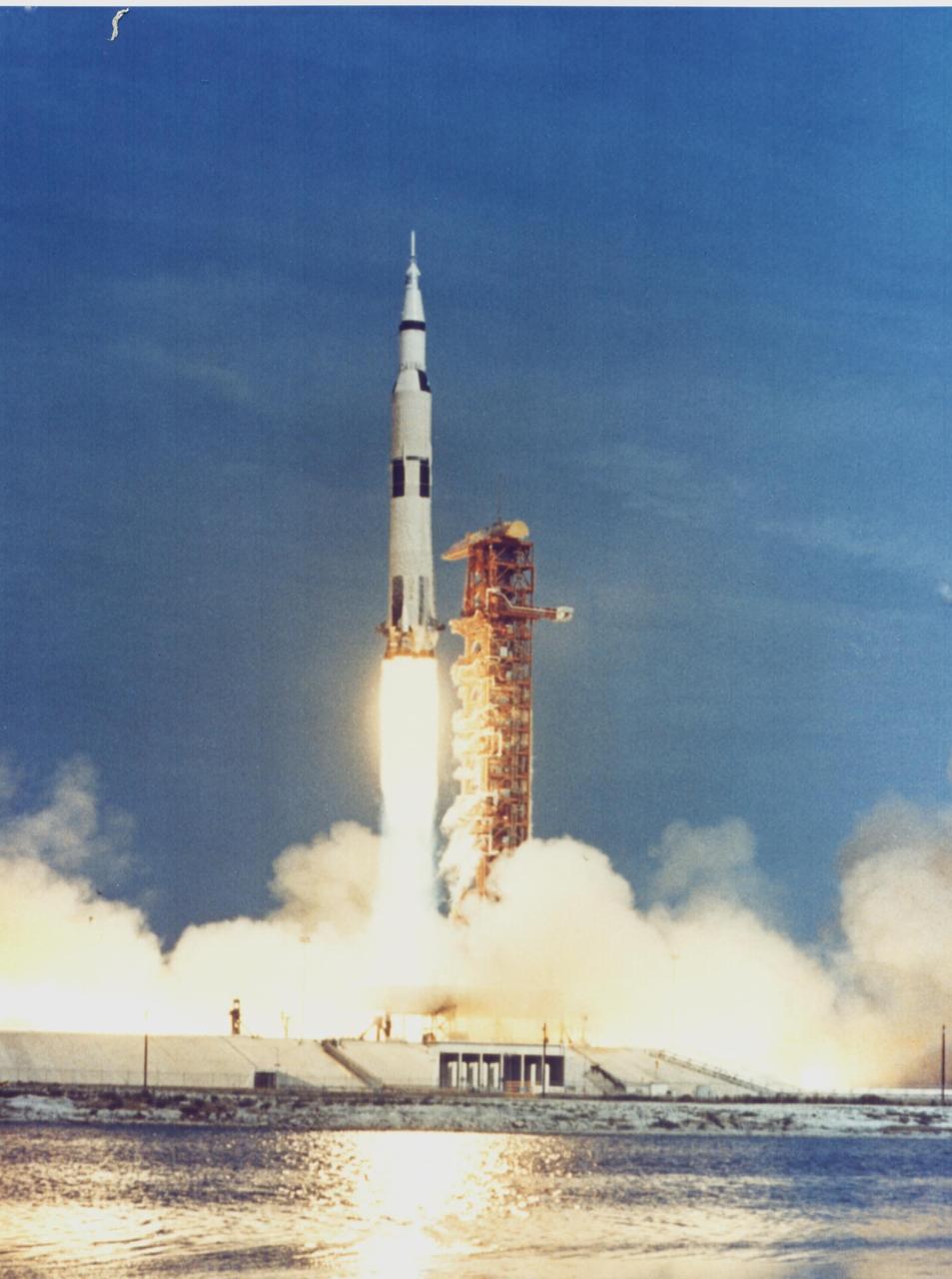 KENNEDY SPACE CENTER, FLA. - The Apollo 11 Saturn V space vehicle rises past the launch tower as it lifts off with astronauts Neil A. Armstrong, Michael Collins and Edwin E. Aldrin Jr. at 9:32 a.m. EDT July 16, 1969, from KSC's Launch Complex 39A. During the planned eight-day mission, Armstrong and Aldrin will descend in a Lunar Module (LM) to the Moon's surface while Collins orbits overhead in the Command Module. The two astronauts are to spend 22 hours on the Moon, including two-and-one-half hours outside the LM. They will gather samples of lunar material and will deploy scientific experiments that will transmit data about the lunar environment. They will rejoin Collins in the Command Module for the return trip to Earth.