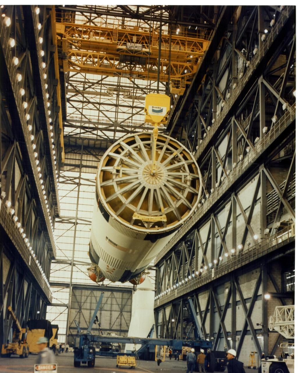 KENNEDY SPACE CENTER, FLA.  - An overhead crane lifts the Saturn V first stage for the Apollo 11 mission from the transfer aisle floor in preparation for stacking on a mobile launcher within the Vehicle Assembly Building's High Bay 1.  The fully assembled vehicle will be called the Apollo/Saturn 506.  The 138-foot-long stage, to which two additional stages -- the instrument unit and the Apollo spacecraft -- will be added, will generate a liftoff thrust of 7.7 million pounds.  Astronauts Neil A. Armstrong, Michael Collins and Edwin E. Aldrin Jr. will pilot the mission which is to include a lunar landing in the lunar module by Armstrong and Aldrin.