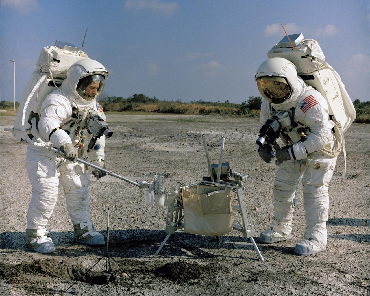 CAPE CANAVERAL, Fla. -- Apollo 13 backup Lunar Module Pilot Charlie Duke, left, scoops up soil at the Kennedy Space Center while backup Commander John Young looks on. Photo credit: NASA
