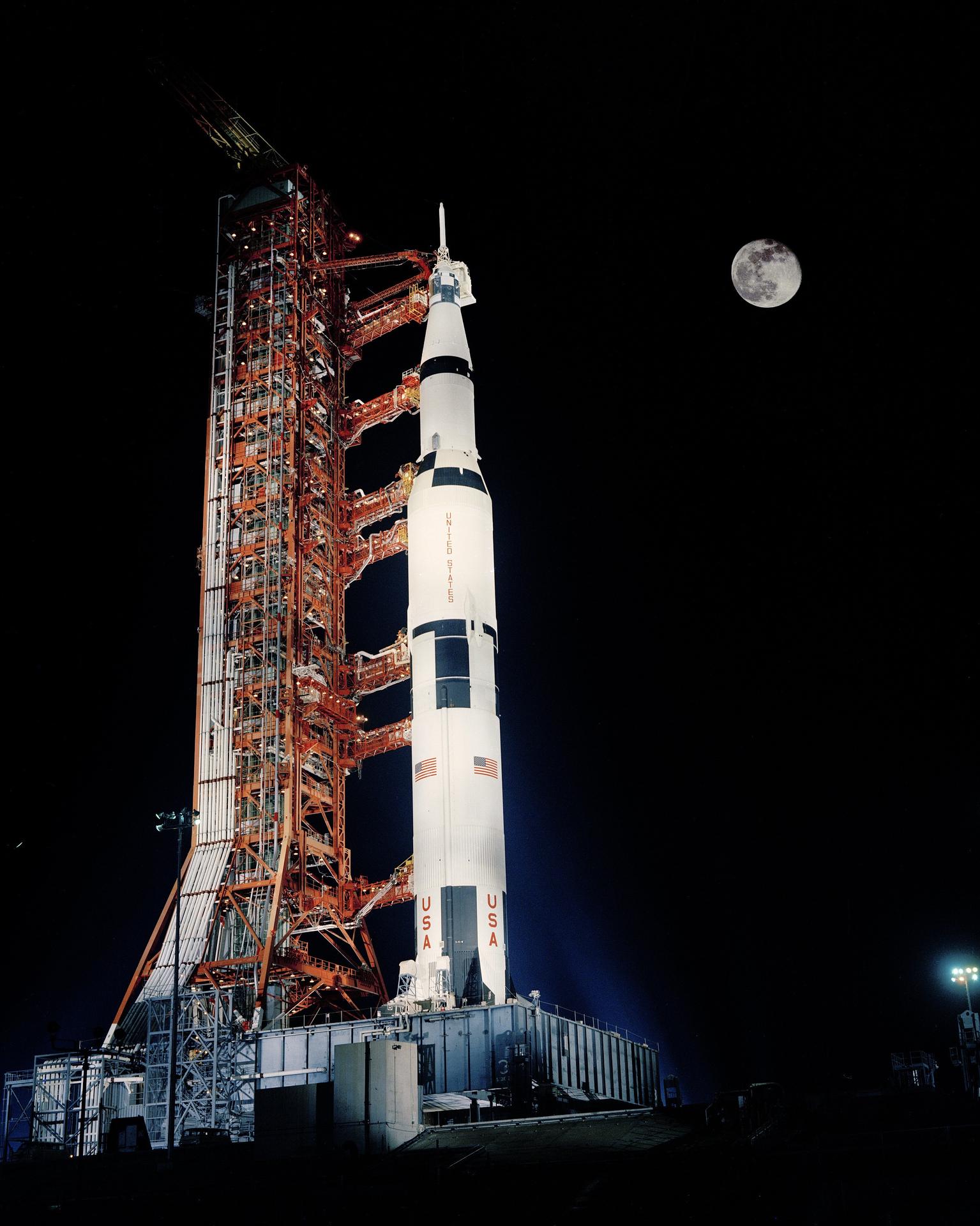 The Apollo 17 Saturn V rocket is lit up beneath a full moon prior to launch