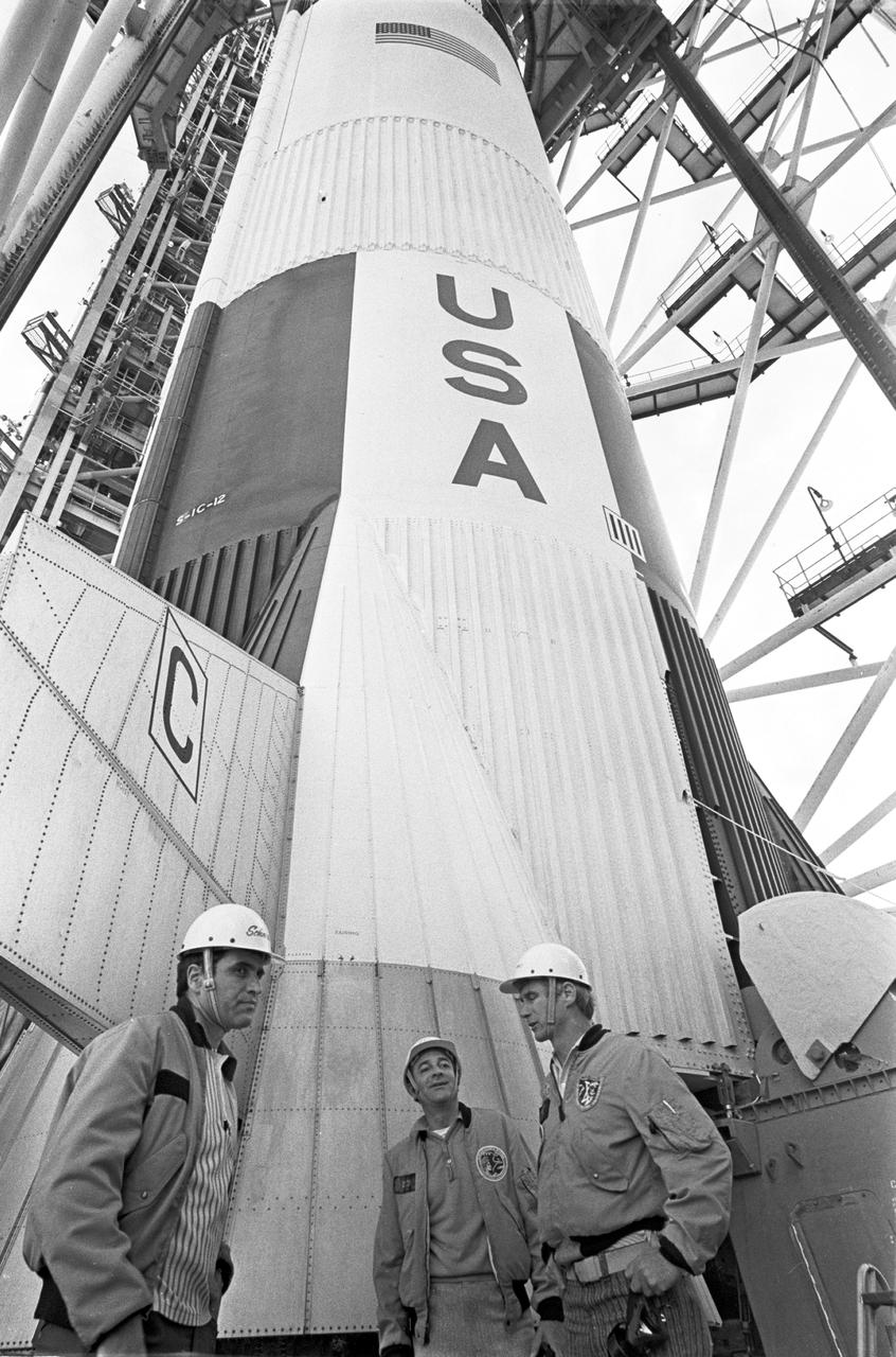 The Apollo 17 space vehicle towers over the astronauts it will launch to the moon on December 6, 1972 from KSC.  The astronauts, L-R, Harrison H. Schmitt, Ronald E. Evans and Eugene A. Cernan participated in a walkdown of the emergency route at Launch complex 39A.