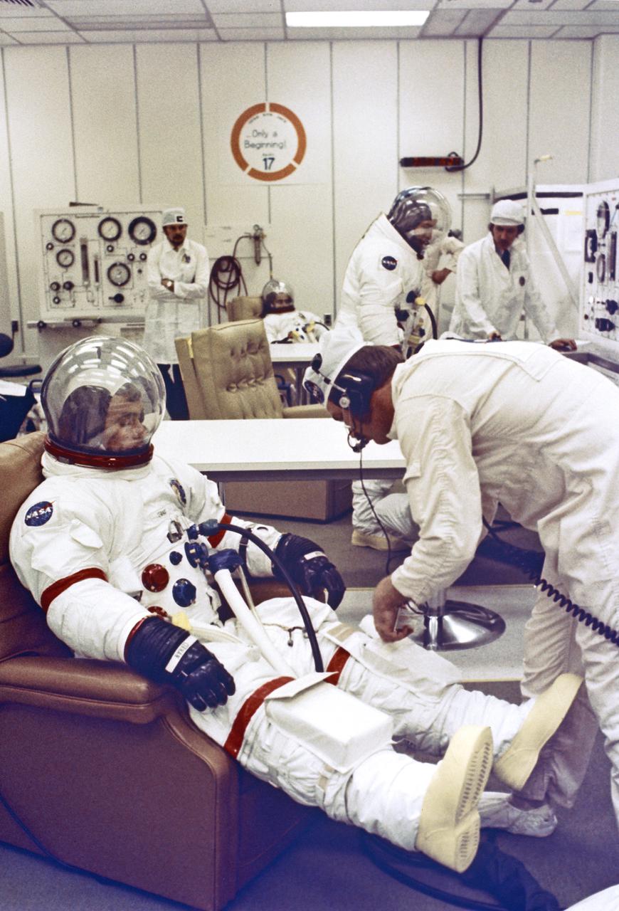 Apollo 17 Commander Eugene A. Cernan undergoes spacesuit Checkout prior to launch to the Moon tonight.  In the background are Command Module Pilot Ronald E. Evans and Lunar Module Pilot Harrison H. Schmitt.