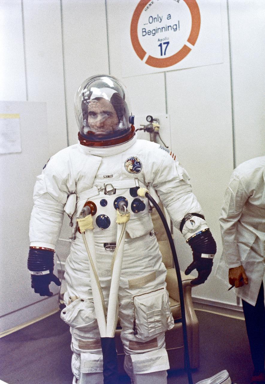 Standing in front of an encouraging sign on the wall, Apollo 17 Lunar Module Pilot Harrison H. Schmitt undergoes spacesuit checks prior to launch to the Moon tonight with astronauts Eugene A. Cernan and Ronald E. Evans.  The wall poster points out that while Apollo 17 may be the last manned mission in the Apollo program NASA has additional on-going manned space flights planned for the future.