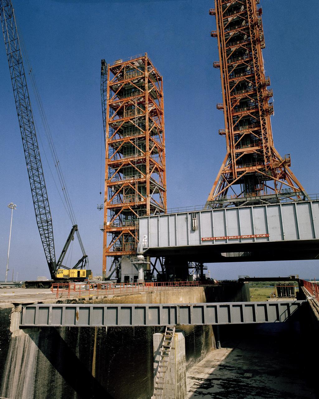 CAPE CANAVERAL, Fla. -- At the Kennedy Space Center in Florida, the shuttle service and access tower SSAT, left, is assembled at Launch Complex 39A from sections of launch umbilical tower 3. The lower 180 feet of the old ML-3 will be topped by the former uppermost section on which a hammerhead crane will be installed and the next lower section which houses the intact ML-3 elevator room and equipment. The SSAT will anchor and support a hinge column to the Payload Changeout Room PCR which will travel on a rail in a specified area to enclose the space shuttle's cargo bay on the pad for installation or removal of payloads. Mobile Launcher 2, center right, is on the pad to support the PCR during construction. Photo Credit: NASA