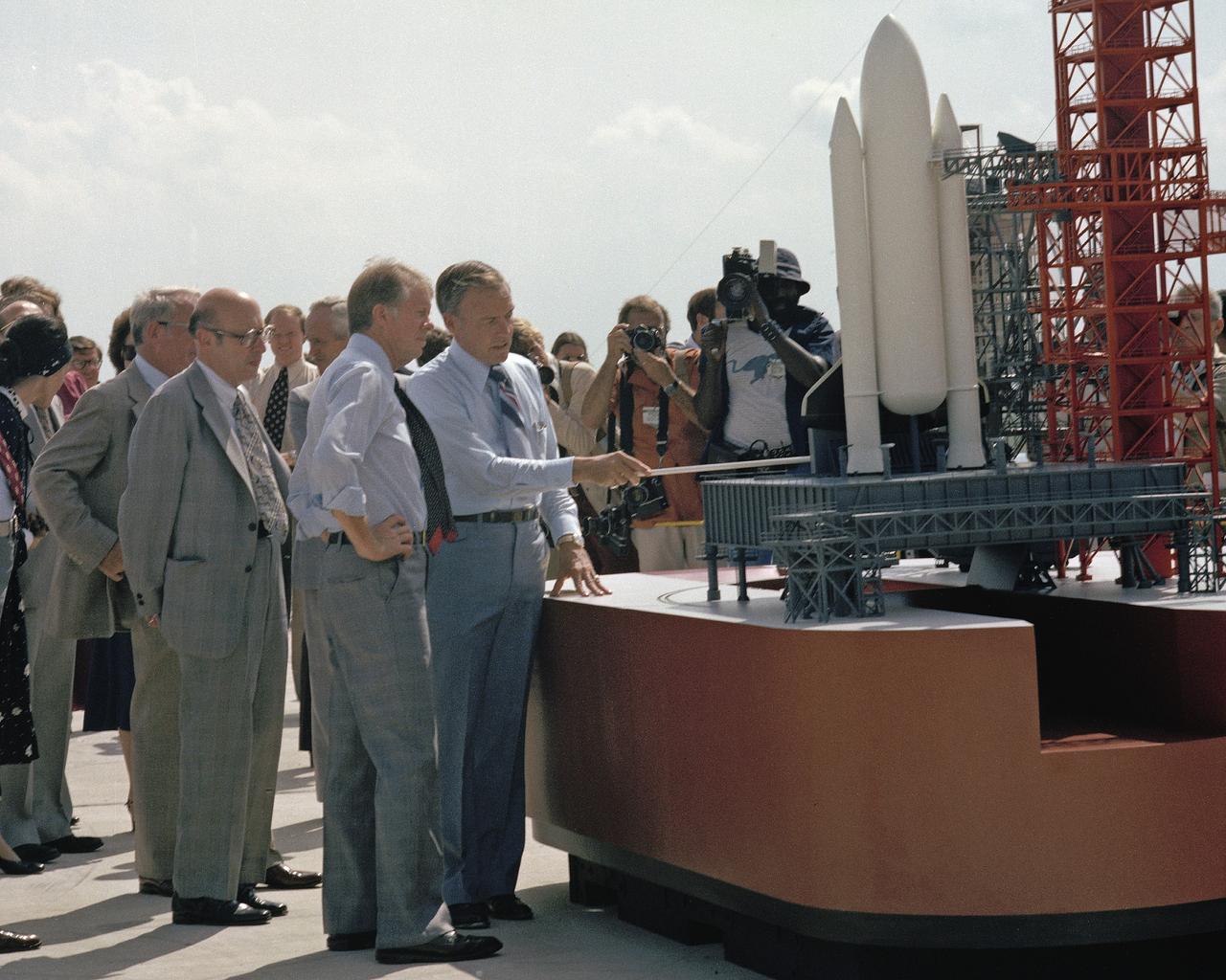 CAPE CANAVERAL, Fla. -- At the Kennedy Space Center in Florida, President Jimmy Carter, hand on waist, is briefed on preparations for the first space shuttle launch by center director Lee Scherer. To the left of Carter is NASA Administrator Robert Frosch. Photo Credit: NASA