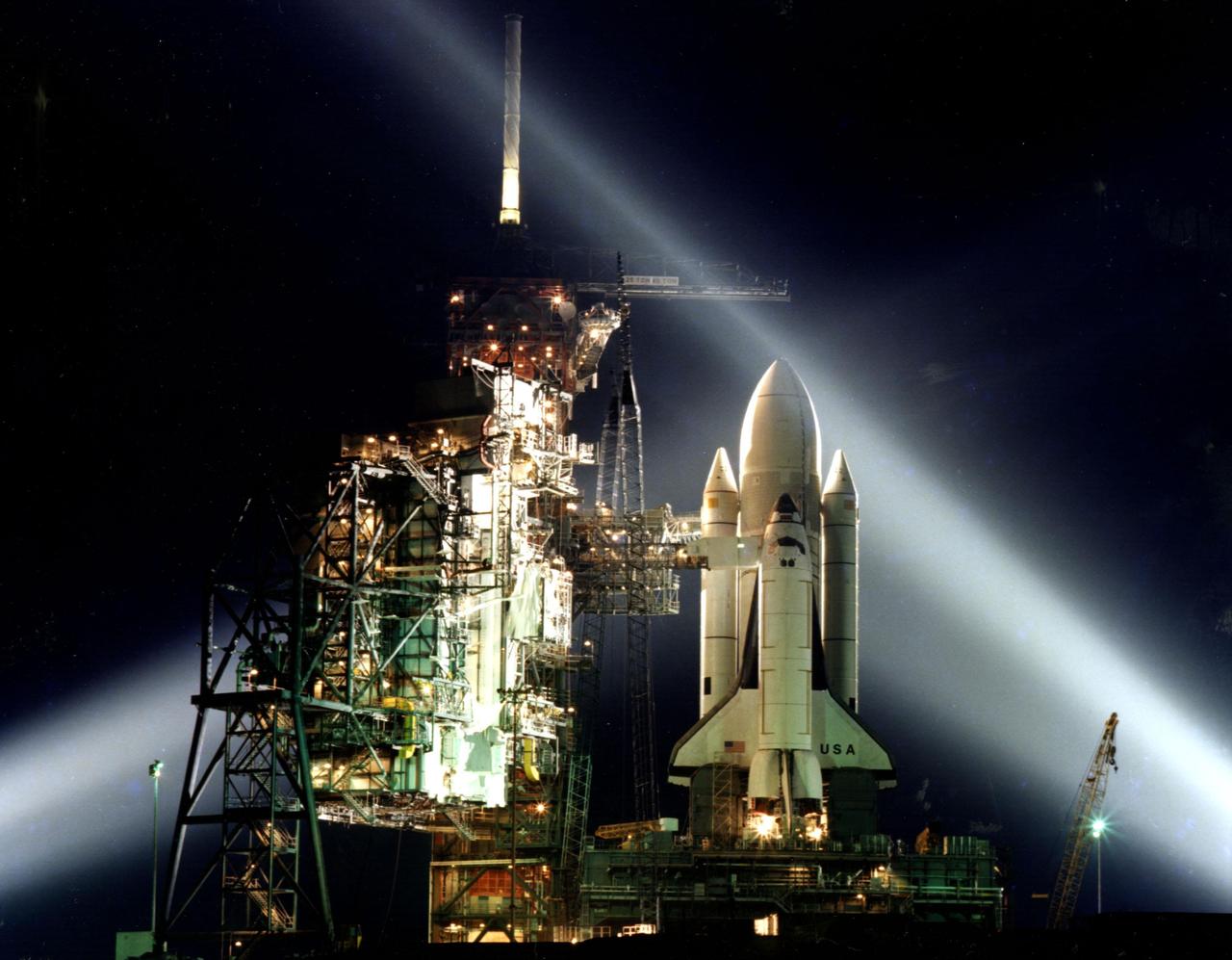 A timed exposure of the first Space Shuttle, STS-1, at Launch Pad A, Complex 39, turns the space vehicle and support facilities into a night-time fantasy of light. To the left of the Shuttle are the fixed and the rotating service structures. 