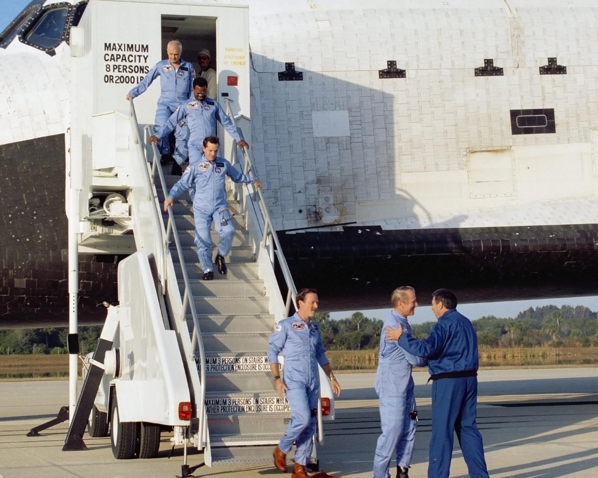 The crew of STS-41B descend a staircase from the space shuttle Challenger