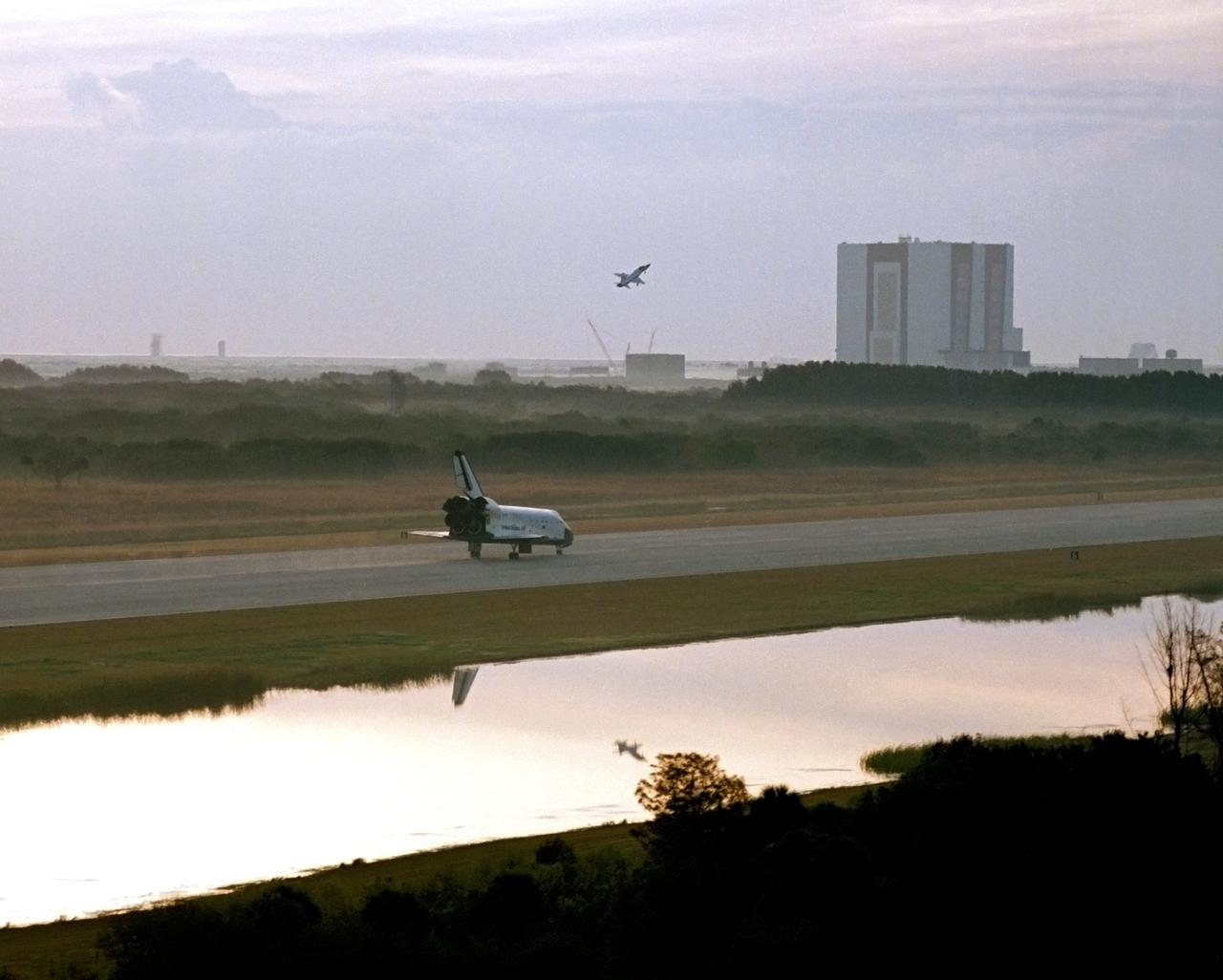 CAPE CANAVERAL, Fla. -- Shortly after sunrise the space shuttle orbiter Challenger touches down on the KSC runway at 7:16 a.m. The T-38 escort chase plane is seen just above the orbiter. The historic first landing at KSC brought to a conclusion an eight-day mission that started at 8:00 a.m. Feb. 3, 1984. The STS 41-B mission had several other firsts including an un-tethered spacewalk made by two of the astronauts. The Vehicle Assembly Building can be seen in the right side of the photograph. Photo credit: NASA