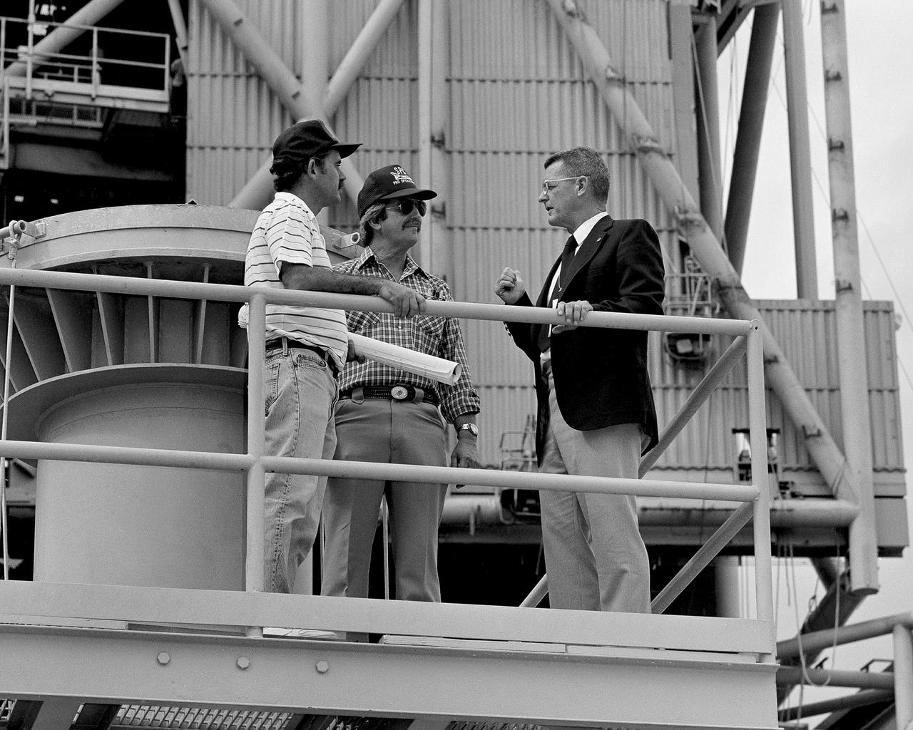 CAPE CANAVERAL, Fla. - Kennedy Space Center Director Forrest McCartney, right, discusses work in progress at Launch Pad 39B as preparations for STS-26 continue. From left are Gary Wall, Lockheed mechanical technician, Joe Spivey, Lockheed hypergolic technician, and McCartney. Photo credit: NASA
