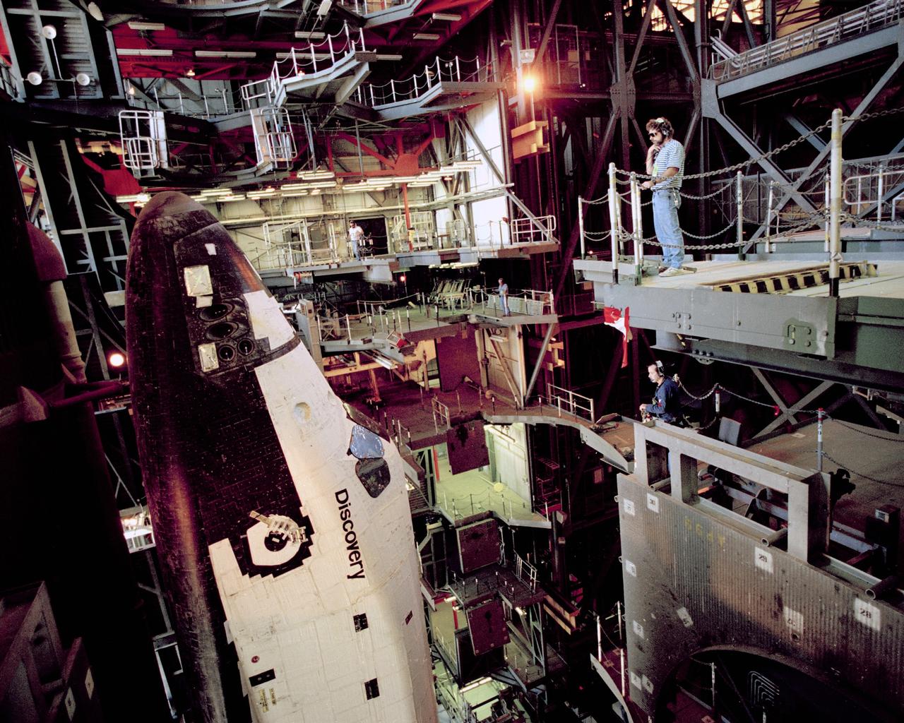 CAPE CANAVERAL, Fla. – Workers watch as the space shuttle Discovery makes the slow journey back from Pad 39A into the Vehicle Assembly Building. After the shuttle is demated, the orbiter will be returned to the Orbiter Processing Facility for repairs to hinges on an orbiter umbilical door. STS-39 is still set to fly this year.    Photo credit: NASA