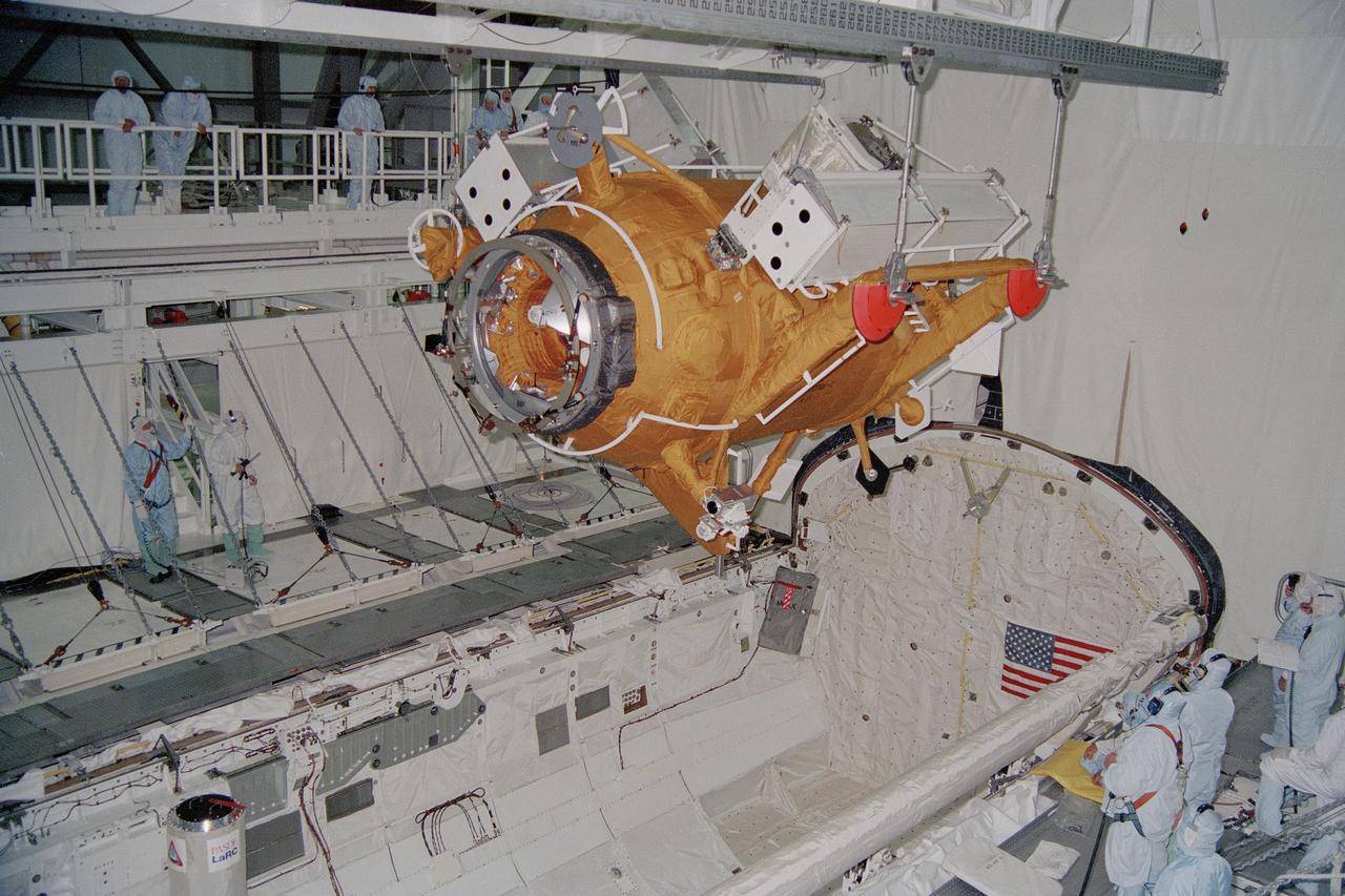 CAPE CANAVERAL, Fla. -- At NASA's Kennedy Space Center in Florida, the Russian-built Docking Module is lowered for installation into the payload bay of the space shuttle Atlantis while it is in bay 2 of the Orbiter Processing Facility. The module will fly as a primary payload on the second Space Shuttle/Mir space station docking mission, STS-74. During the mission, the module will first be attached with the orbiter's robot arm to the Orbiter Docking System in the payload bay of the orbiter Atlantis and then be docked with the Mir. When Atlantis undocks from the Mir, it will leave the new docking module permanently attached to the space station for use during future shuttle Mir docking missions. The new module will simplify future Shuttle linkups with Mir by improving orbiter clearances when it serves as a bridge between the two spacecraft. The white structures attached to the module's sides are solar panels that will be attached to the Mir after the conclusion of the STS-74 mission. Photo Credit: NASA
