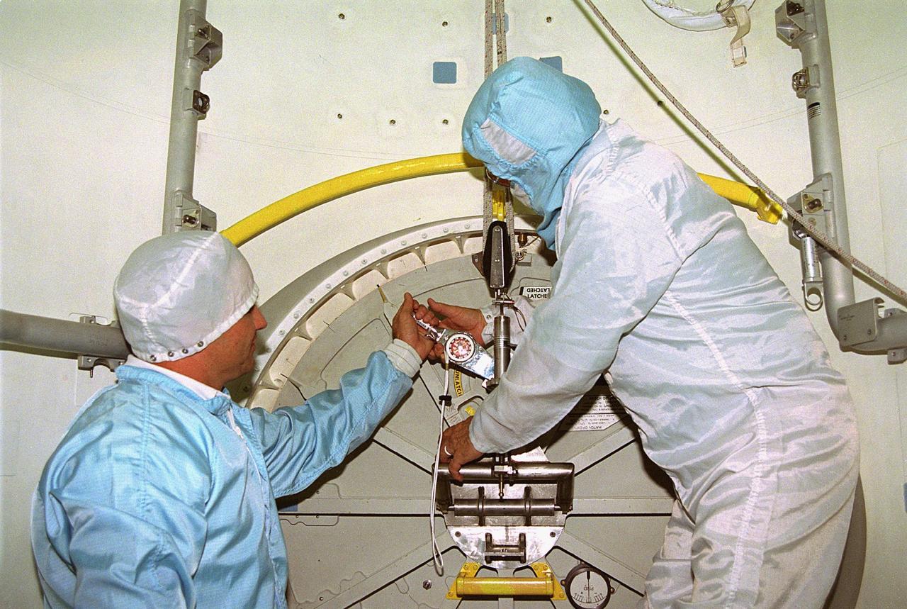 KENNEDY SPACE CENTER, FLA. -- In Orbiter Processing Facility Bay 1, United Space Alliance (USA) technicians Dave Lawrence, at left, and James Cullop troubleshoot the orbiter Columbia’s outer hatch of the airlock, which failed to open during the recent STS-80 Space Shuttle mission. Mission Specialists Tamara E. Jernigan and Thomas D. Jones did not perform the mission’s planned two extravehicular activities (EVAs) or spacewalks because the hatch would not open on orbit. The spacewalks were to be part of the continuing series of EVA Development Flight Tests to evaluate equipment and procedures and to build spacewalking experience in preparation for the International Space Station.