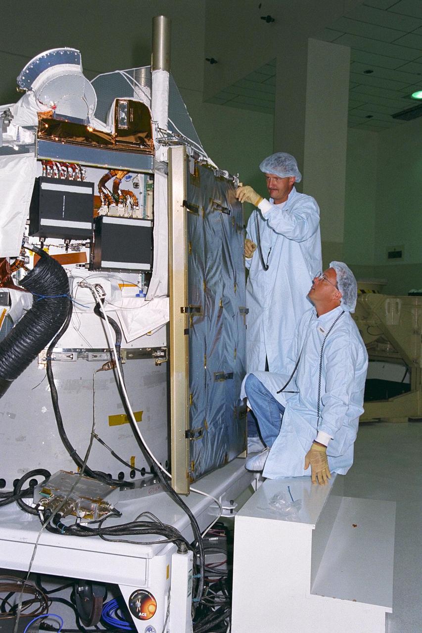 Applied Physics Laboratory Engineer Cliff Willey (kneeling) and Engineering Assistant Jim Hutcheson from Johns Hopkins University install solar array panels on the Advanced Composition Explorer (ACE) in KSC’s Spacecraft Assembly and Encapsulation Facility-II. Scheduled for launch on a Delta II rocket from Cape Canaveral Air Station on Aug. 25, ACE will study low-energy particles of solar origin and high-energy galactic particles for a better understanding of the formation and evolution of the solar system as well as the astrophysical processes involved. The ACE observatory will be placed into an orbit almost a million miles (1.5 million kilometers) away from the Earth, about 1/100 the distance from the Earth to the Sun. The collecting power of instrumentation aboard ACE is at least 100 times more sensitive than anything previously flown to collect similar data by NASA
