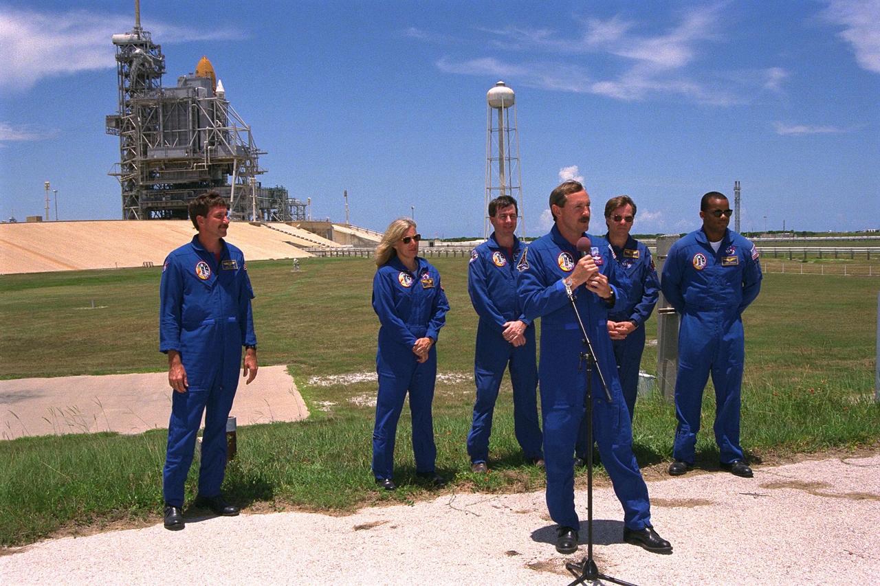 KENNEDY SPACE CENTER, Fla. -- STS-85 Commander Curtis L. Brown, Jr.,  addresses the news media at a briefing at Launch Pad 39A while the other members of the   flight crew in the background prepare to field questions during a break in Terminal  Countdown Demonstration Test (TCDT) activities for that mission. They are (back row,  from left): Pilot Kent V. Rominger; Payload Commander N. Jan Davis; Mission  Specialist Stephen K. Robinson; Payload Specialist Bjarni V. Tryggvason; and Mission  Specialist Robert L. Curbeam, Jr.  The primary payload aboard the Space Shuttle orbiter  Discovery is the Cryogenic Infrared Spectrometers and Telescopes for the Atmosphere-2  (CRISTA-SPAS-2).  Other payloads on the 11-day mission include the Manipulator Flight  Demonstration (MFD), and Technology Applications and Science-1 (TAS-1) and   International Extreme Ultraviolet Hitchhiker-2 (IEH-2) experiments