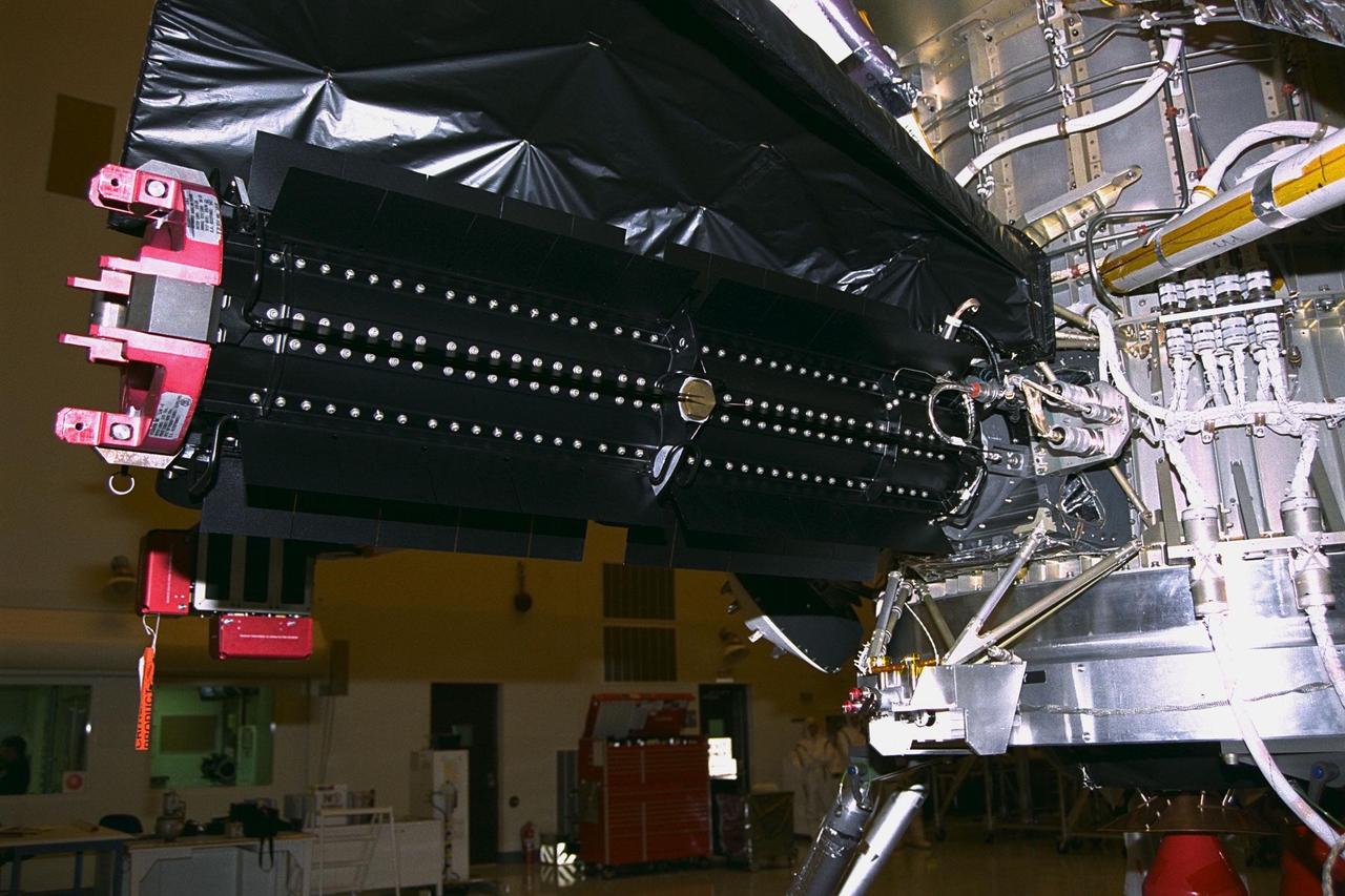 This radioisotope thermoelectric generator (RTG), at  center, is ready for electrical verification testing now that it has been installed on the Cassini  spacecraft in the Payload Hazardous Servicing Facility. A handling fixture, at far left,  remains attached. This is the third and final RTG to be installed on Cassini for the  prelaunch tests. The RTGs will provide electrical power to Cassini on its 6.7-year trip to  the Saturnian system and during its four-year mission at Saturn. RTGs use heat from  the natural decay of plutonium to generate electric power. The generators enable  spacecraft to operate at great distances from the Sun where solar power systems are  not feasible. The Cassini mission is targeted for an Oct. 6 launch aboard a Titan  IVB/Centaur expendable launch vehicle