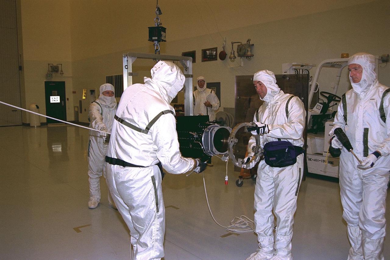 Workers in the Payload Hazardous Servicing Facility   remove the storage collar from a radioisotope thermoelectric generator (RTG) in  preparation for installation on the Cassini spacecraft. Cassini will be outfitted with three  RTGs. The power units are undergoing mechanical and electrical verification tests in the  PHSF. The RTGs will provide electrical power to Cassini on its 6.7-year trip to the  Saturnian system and during its four-year mission at Saturn. RTGs use heat from the  natural decay of plutonium to generate electric power. The generators enable spacecraft  to operate at great distances from the Sun where solar power systems are not feasible.  The Cassini mission is targeted for an Oct. 6 launch aboard a Titan IVB/Centaur  expendable launch vehicle