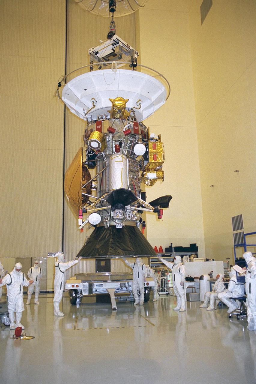Flight mechanics from NASA’s Jet Propulsion Laboratory (JPL) in Pasadena, Calif., lift the Cassini spacecraft along with its launch vehicle adapter in KSC’s Payload Hazardous Servicing Facility. The black conical-shaped adapter seen at the bottom of the spacecraft will later be mated to a Titan IV/Centaur expendable launch vehicle that will lift Cassini into space. Scheduled for launch in October, the Cassini mission seeks insight into the origins and evolution of the early solar system. Scientific instruments carried aboard the spacecraft will study Saturn’s atmosphere, magnetic field, rings, and several moons. JPL is managing the Cassini project for NASA