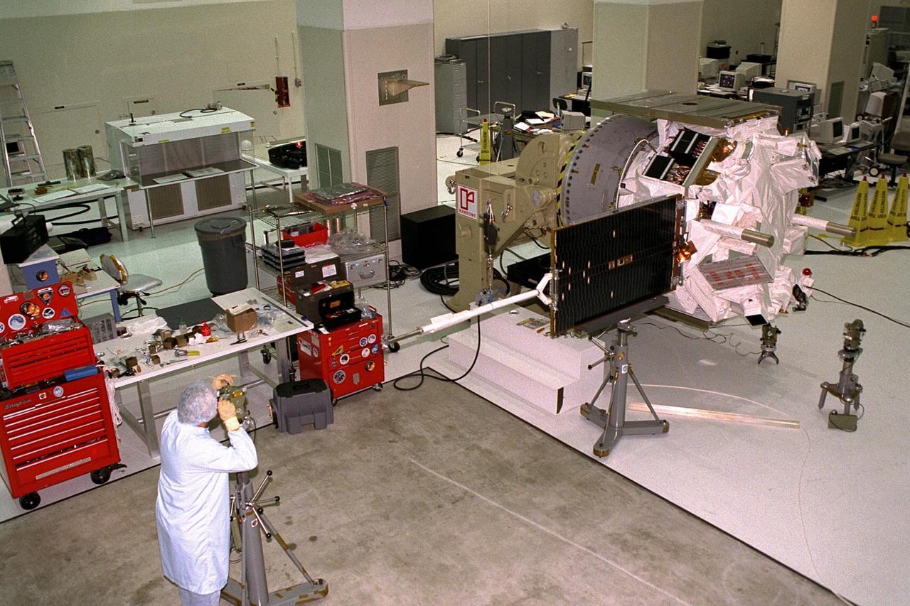An Applied Physics Laboratory engineer from Johns Hopkins University tests for true perpendicular solar array deployment of the Advanced Composition Explorer (ACE) in KSC’s Spacecraft Assembly and Encapsulation Facility-II (SAEF-II). The white magnetometer boom seen across the solar array panel will deploy the panel once in space. Scheduled for launch on a Delta II rocket from Cape Canaveral Air Station on Aug. 25, ACE will study low-energy particles of solar origin and high-energy galactic particles. The ACE observatory will be placed into an orbit almost a million miles (1.5 million kilometers) away from the Earth, about 1/100 the distance from the Earth to the Sun