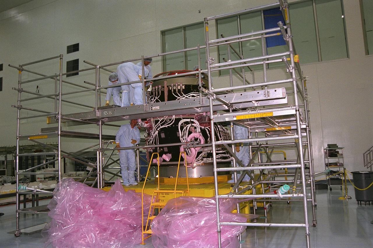 International Space Station (ISS) contractors erect access scaffolding around the Pressurized Mating Adapter-1 (PMA-1) for the ISS in KSC’s Space Station Processing Facility. A PMA is a cone-shaped connector that will be attached to Node 1, the space station’s structural building block, during ground processing. The white flight cables around PMA-1 will assist in connecting the node to the U.S.-financed, Russian-built Functional Cargo Block, a component that supplies early power and propulsion systems for the station. Node 1 with two adapters attached will be the first element of the station to be launched aboard the Space Shuttle Endeavour on STS-88 in July 1998