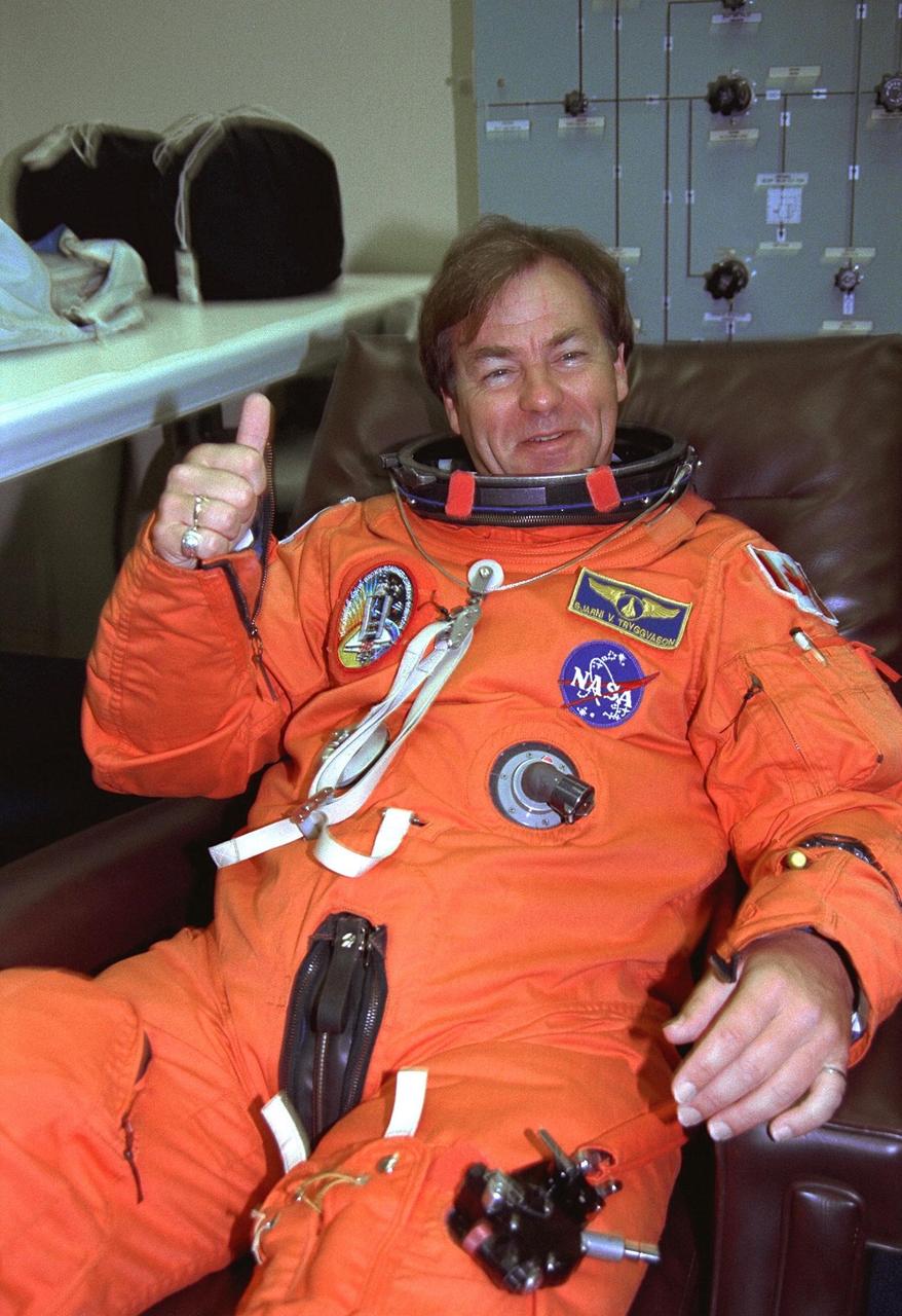 STS-85 Payload Specialist Bjarni V. Tryggvason gives a thumbs up as he is assisted with his ascent/reentry flight suit in the Operations and Checkout (O&C) Building. He is a Canadian Space Agency astronaut and was born in Iceland. Tryggvason has also been a flight instructor for the Canadian Air Force. Tryggvason is the principal investigator of the Microgravity Vibration Isolation Mount now flying on the Russian Mir space station. During STS-85, Tryggvason will conduct vibration isolation mount and fluid physics investigations. His work to study how Shuttle vibrations affect the results of experiments will be valuable to the International Space Station program, since this experiment is planned for use on that space platform. Tryggvason will also conduct Bioreactor experiments and assist Mission Specialist Stephen K. Robinson with photography