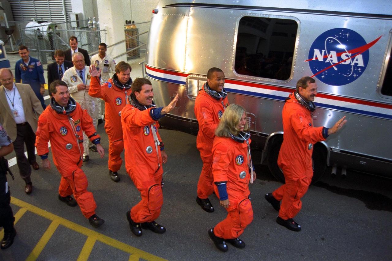 The STS-85 flight crew greets a crowd of well-wishers as they walk out of the Operations and Checkout (O&C) Building to board the Astrovan for their ride to Launch Pad 39A, where they will take their places aboard the Space Shuttle Discovery. Waving to the crowd is Commander Curtis L. Brown, Jr.(right), followed by Payload Commander N. Jan Davis, Mission Specialist Robert L. Curbeam, Jr., Pilot Kent V. Rominger, Mission Specialist Stephen K. Robinson and Payload Specialist Bjarni V. Tryggvason. The primary payload aboard the Space Shuttle orbiter Discovery is the Cryogenic Infrared Spectrometers and Telescopes for the Atmosphere-Shuttle Pallet Satellite-2 (CRISTA-SPAS-2) free-flyer. Other payloads on the 11-day mission include the Manipulator Flight Demonstration (MFD), and Technology Applications and Science-1 (TAS-1) and International Extreme Ultraviolet Hitchhiker-2 (IEH-2) experiments