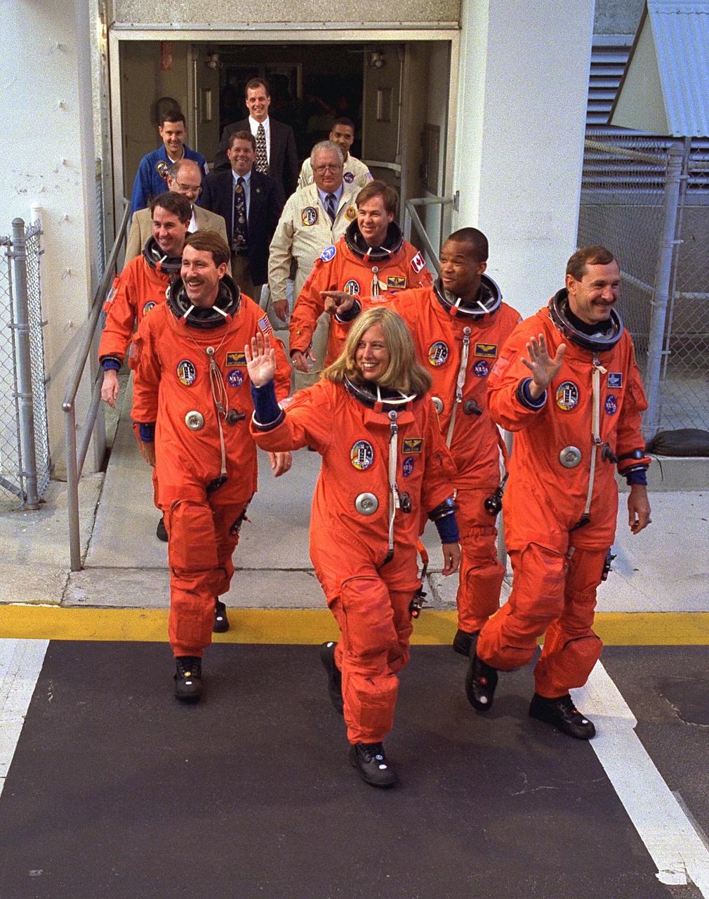 KENNEDY SPACE CENTER, FLA. -- The STS-85 flight crew greets a crowd of well-wishers as they walk out of the Operations and Checkout (O&C) Building for their ride to Launch Pad 39A, where they will take their places aboard the Space Shuttle Discovery. Waving to the crowd is Commander Curtis L. Brown, Jr.(right). Directly behind him are Mission Specialist Robert L. Curbeam, Jr. and Payload Specialist Bjarni V. Tryggvason. To Brown’s right is Payload Commander N. Jan Davis. Directly behind her are Pilot Kent V. Rominger and Mission Specialist Stephen K. Robinson. The primary payload aboard the Space Shuttle orbiter Discovery is the Cryogenic Infrared Spectrometers and Telescopes for the AtmosphereShuttle Pallet Satellite-2 (CRISTA-SPAS-2) free-flyer. Other payloads on the 11-day mission include the Manipulator Flight Demonstration (MFD), and Technology Applications and Science-1 (TAS-1) and International Extreme Ultraviolet Hitchhiker-2 (IEH-2) experiments