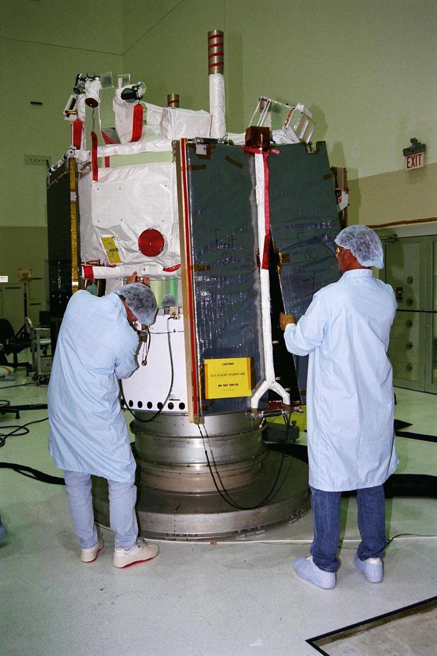 The Advanced Composition Explorer (ACE) undergoes final prelaunch processing in KSC’s Spacecraft Assembly and Encapsulation Facility-2 (SAEF-2) before being transported to Pad A at Launch Complex 17, Cape Canaveral Air Station, for mating to the Delta II launch vehicle. This photo was taken during a news media opportunity. The worker at right is installing protective covering over one of the spacecraft’s solar arrays. ACE with its combination of nine sensors and instruments will investigate the origin and evolution of solar phenomenon, the formation of solar corona, solar flares and acceleration of the solar wind. Launch is targeted for Aug. 24