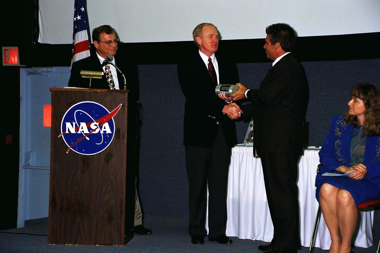 KENNEDY SPACE CENTER, FLA. -- William Saputo, L-3 Communications, presents a new piece of technology, developed through a National Aeronautics and Space Administration (NASA) partnership with industry, to Kennedy Space Center (KSC) Director Roy Bridges, Jr. (second from left). The piece of technology being presented, the Universal Signal Conditioning Amplifier (USCA), is a key component of the codeveloped Automated Data Acquisition System (ADAS) that measures temperature, pressure and vibration at KSC's launch pads. The breakthrough technology is expected to reduce sensor setup and configuration times from hours to seconds. KSC teamed up with Florida's Technological Research and Development Authority and manufacturer L-3 Communications to produce a system that would benefit the aerospace industry and other commercial markets