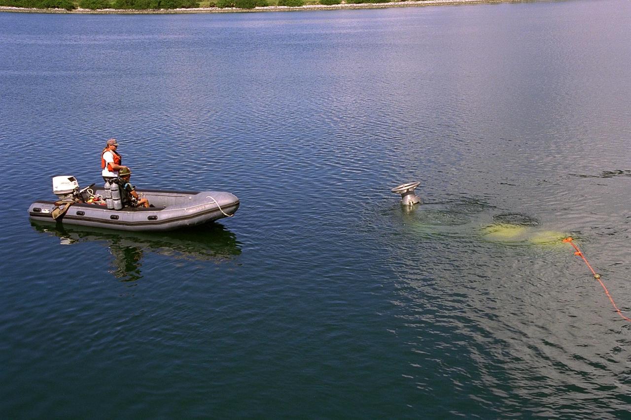 KENNEDY SPACE CENTER, FLA. -- A scuba diver stands by as the unmanned Max Rover submersible goes down to insert a Diver Operated Plug (DOP) into an aft nozzle like the ones used on the Space Shuttle's solid rocket boosters (SRBs). NASA and contractor Deep Sea Systems demonstrated the submersible at Port Canaveral's Trident pier. Kennedy Space Center's SRB retrieval team and Advanced Systems Development laboratory staff hope that the new robotic technology will make the process of inserting the plug into spent SRBs safer and less strenuous. Currently, scuba divers manually insert the DOP into the aft nozzle of a jettisoned SRB 60 to 70 feet below the surface of the Atlantic Ocean. After the plug is installed, water is pumped out of the booster allowing it to float horizontally. It is then towed back to Hangar AF at Cape Canaveral Air Station for refurbishment. Deep Sea Systems of Falmouth, Mass., built the submersible for NASA