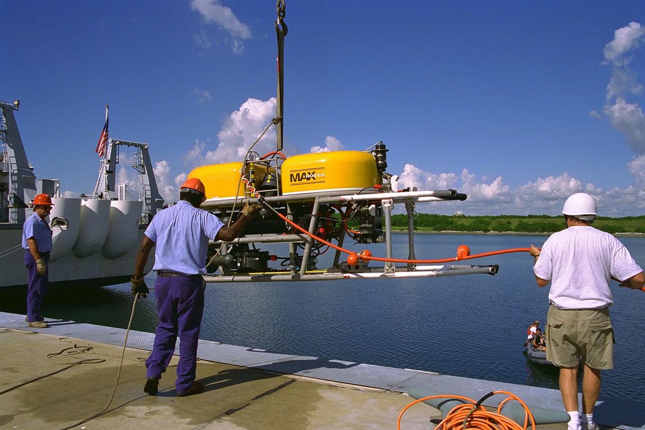KENNEDY SPACE CENTER, FLA. -- Technicians lower the unmanned robotic submersible recovery system, known as Max Rover, into the water at the Trident Pier at Port Canaveral during a test of the system. Kennedy Space Center's solid rocket booster (SRB) retrieval team and Advanced Systems Development laboratory staff hope that the new robotic technology will make the process of inserting the Diver Operated Plug (DOP) into the aft nozzle of a spent SRB safer and less strenuous. Currently, scuba divers manually insert the DOP into the aft nozzle of a jettisoned SRB 60 to 70 feet below the surface of the Atlantic Ocean. After the plug is installed, water is pumped out of the booster allowing it to float horizontally. It is then towed back to Hangar AF at Cape Canaveral Air Station. Deep Sea Systems of Falmouth, Mass., built the submersible for NASA