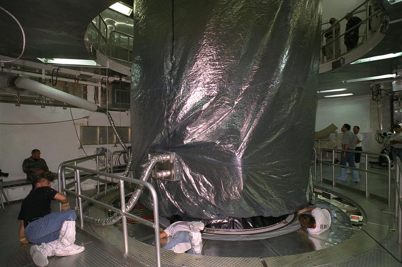 Technicians at Cape Canaveral Air Station (CCAS) begin to remove the transportation cover from the Cassini spacecraft after it was lifted to the top of the Titan IV/Centaur launch vehicle at Complex 40. Cassini is an international mission conducted by the National Aeronautics and Space Administration (NASA), the European Space Agency (ESA), and the Italian Space Agency (ASI). The two-story-tall spacecraft, scheduled for launch on Oct. 6, is destined to arrive at Saturn in July 2004, where it will orbit and study Saturn, its rings, moons and magnetic environment in detail over a four-year period. The Cassini mission is managed for NASA's Office of Space Science by the Jet Propulsion Laboratory, a division of the California Institute of Technology