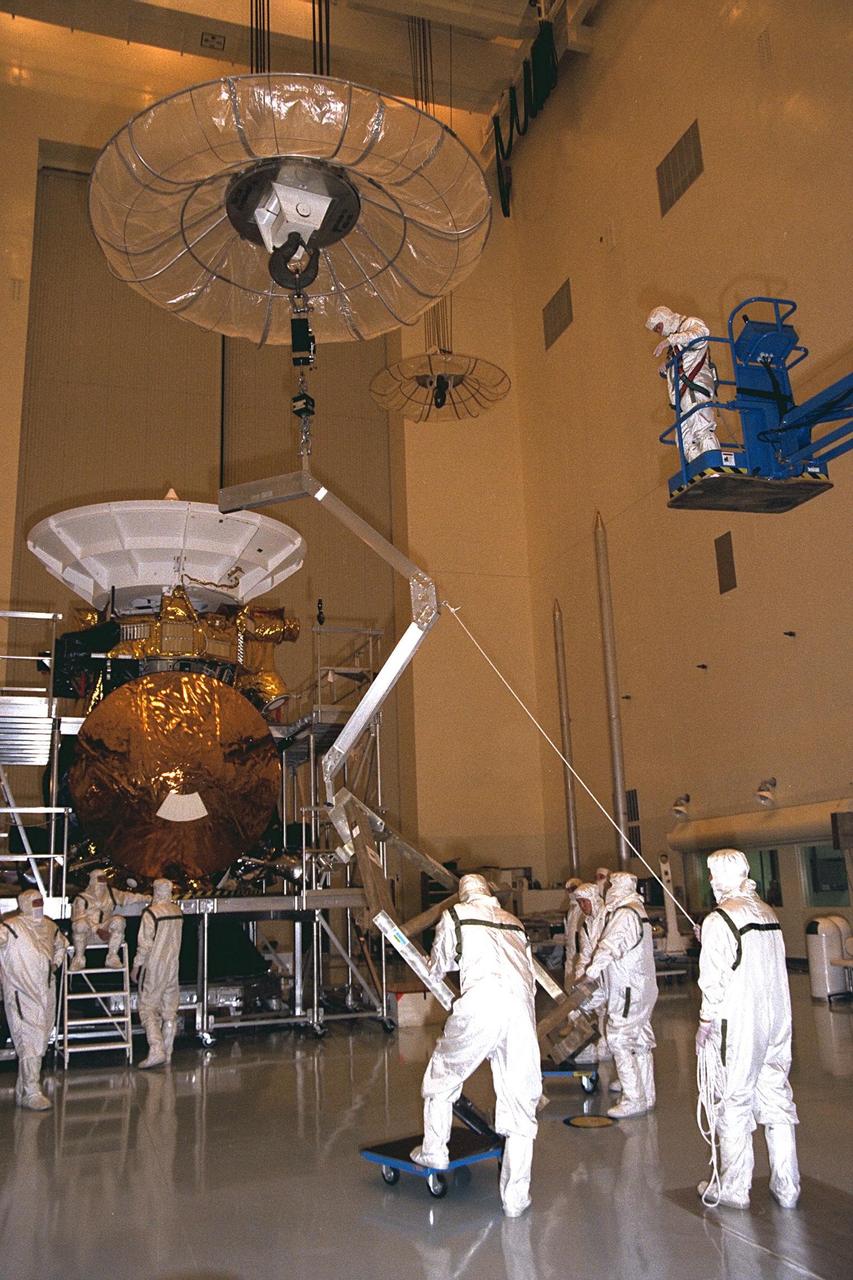 Workers remove the Huygens probe from the Cassini spacecraft in the Payload Hazardous Servicing Facility (PHSF) at KSC. The spacecraft was returned to the PHSF after damage to thermal insulation was discovered inside Huygens from an abnormally high flow of conditioned air. Further internal inspection, insulation repair and a cleaning of the probe are now required. Mission managers are targeting a mid-October launch date after Cassini returns to the pad and is once again placed atop its Titan IVB expendable launch vehicle at Launch Pad 40 at Cape Canaveral Air Station