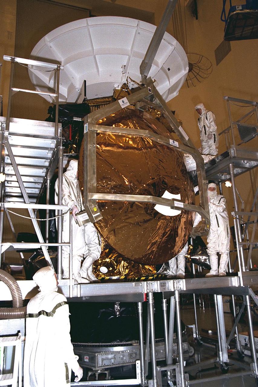 Workers remove the Huygens probe from the Cassini spacecraft in the Payload Hazardous Servicing Facility (PHSF) at KSC. The spacecraft was returned to the PHSF after damage to thermal insulation was discovered inside Huygens from an abnormally high flow of conditioned air. Further internal inspection, insulation repair and a cleaning of the probe are now required. Mission managers are targeting a mid-October launch date after Cassini returns to the pad and is once again placed atop its Titan IVB expendable launch vehicle at Launch Pad 40 at Cape Canaveral Air Station