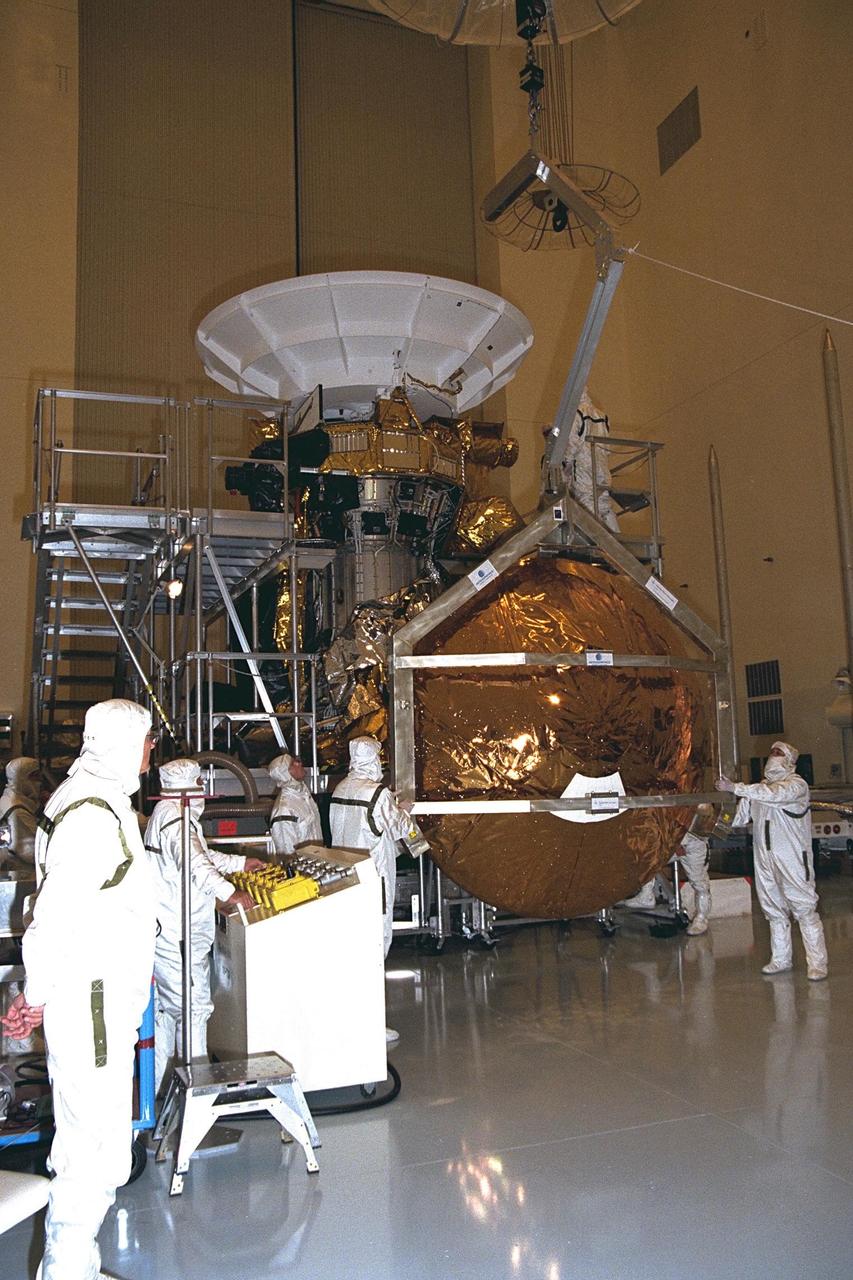 Workers remove the Huygens probe from the Cassini spacecraft in the Payload Hazardous Servicing Facility (PHSF) at KSC. The spacecraft was returned to the PHSF after damage to thermal insulation was discovered inside Huygens from an abnormally high flow of conditioned air. Further internal inspection, insulation repair and a cleaning of the probe are now required. Mission managers are targeting a mid-October launch date after Cassini returns to the pad and is once again placed atop its Titan IVB expendable launch vehicle at Launch Pad 40 at Cape Canaveral Air Station