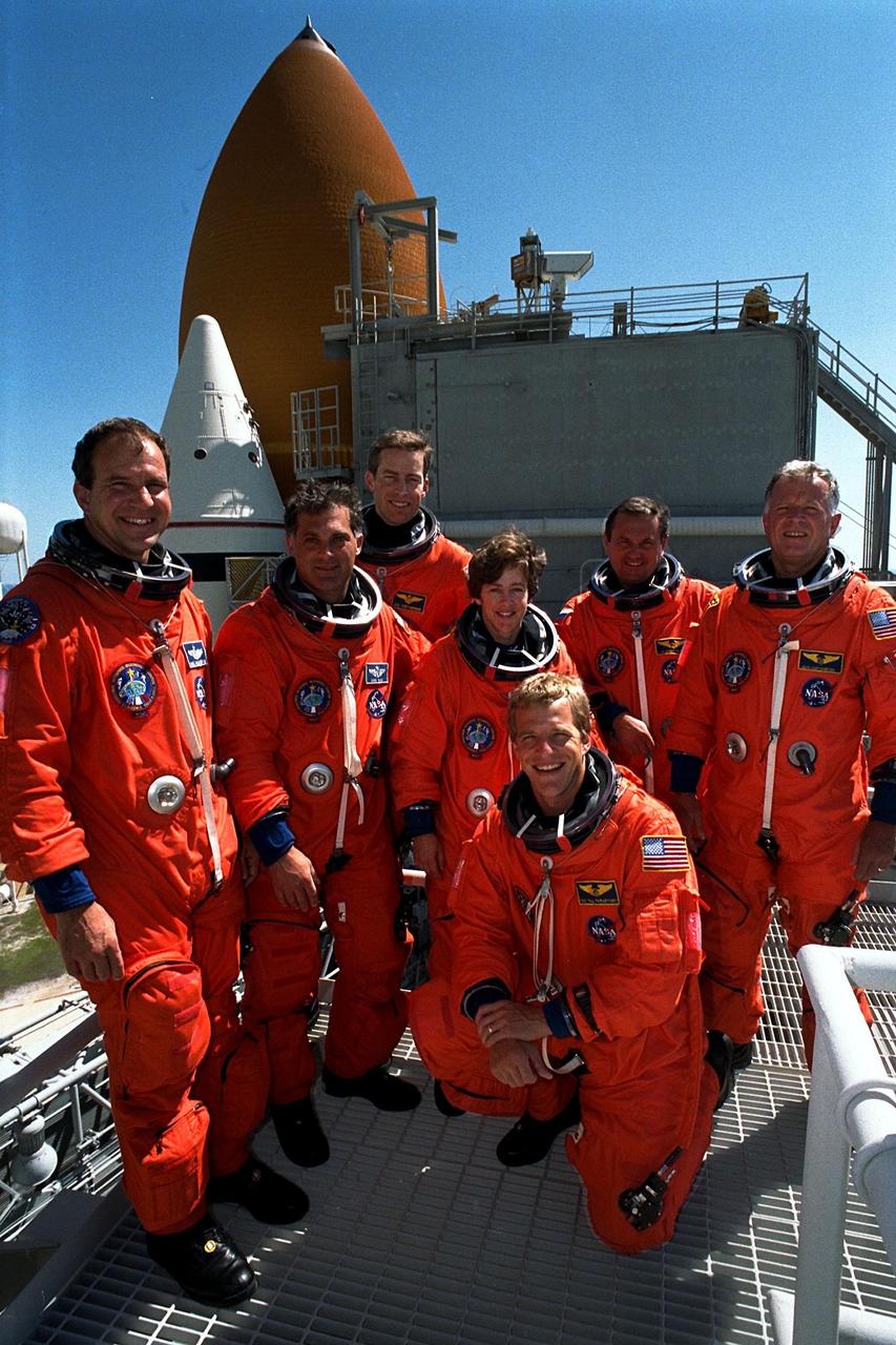 KENNEDY SPACE CENTER, Fla. -- With the Space Shuttle Atlantis behind then, STS-86 crew members pose for a group photograph at Launch Pad 39A. Kneeling in front is Mission Specialist Scott E. Parazynski. From left, are Pilot Michael J. Bloomfield, Mission Specialist David A. Wolf, Commander James D. Wetherbee, and Mission Specialists Wendy B. Lawrence, Vladimir Georgievich Titov of the Russian Space Agency, and Jean-Loup J.M. Chretien of the French Space Agency, CNES. STS-86 will be the seventh docking of the Space Shuttle with the Russian Space Station Mir. Liftoff is targeted for Sept. 25