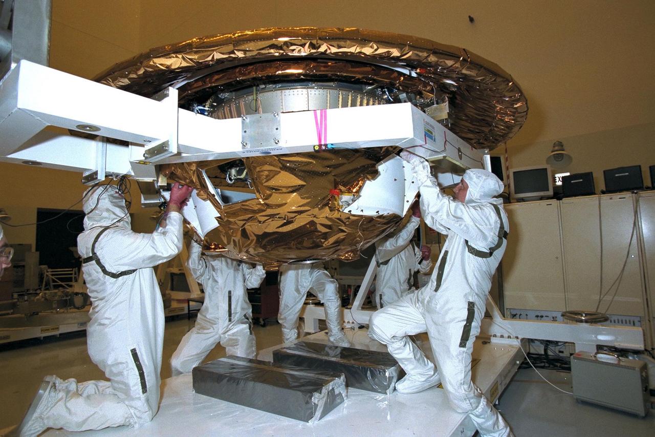 Dornier Satelliten Systeme (DSS) workers place the back cover of the Huygens probe under its front heat shield in the Payload Hazardous Servicing Facility (PHSF) at KSC. The spacecraft was returned to the PHSF after damage to thermal insulation was discovered inside Huygens from an abnormally high flow of conditioned air. Internal inspection, insulation repair and a cleaning of the probe were required. Mission managers are targeting a mid-October launch date after the Cassini spacecraft, aboard which Huygens will be launched, returns to the pad and is once again placed atop its Titan IVB expendable launch vehicle at Launch Pad 40 at Cape Canaveral Air Station
