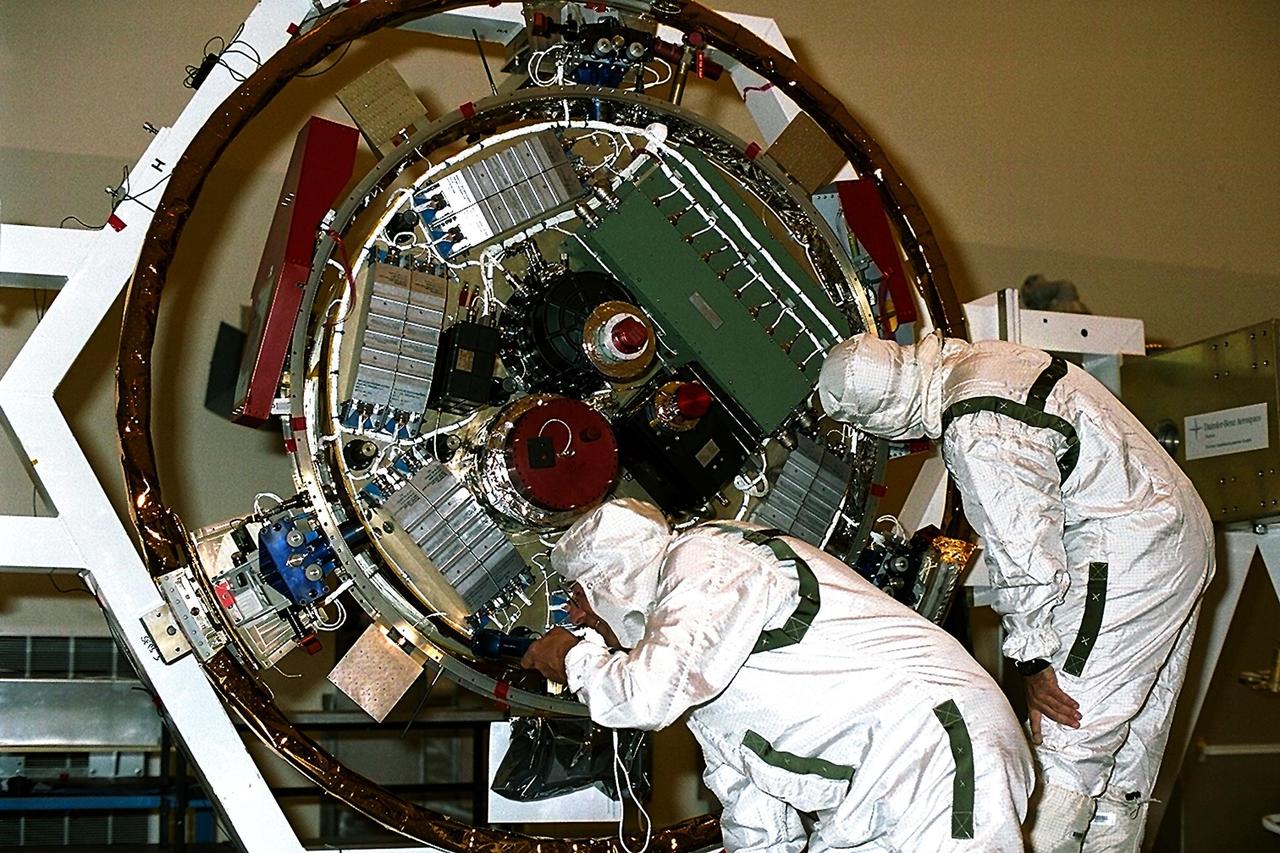 Jet Propulsion Laboratory (JPL) workers examine the Huygens probe after removal from the Cassini spacecraft in the Payload Hazardous Servicing Facility (PHSF) at KSC. The spacecraft was returned to the PHSF after damage to thermal insulation was discovered inside Huygens from an abnormally high flow of conditioned air. Internal inspection, insulation repair and a cleaning of the probe were required. Mission managers are targeting a mid-October launch date after Cassini returns to the pad and is once again placed atop its Titan IVB expendable launch vehicle at Launch Pad 40 at Cape Canaveral Air Station
