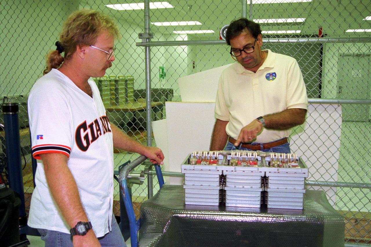 Boeing technicians John Pearce Jr., at left, and Mike Vawter prepare a Russian replacement computer for stowage aboard the Space Shuttle Atlantis shortly before the scheduled launch of Mission STS-86, slated to be the seventh docking of the Space Shuttle with the Russian Space Station Mir. The preparations are being made at the SPACEHAB Payload Processing Facility in Cape Canaveral. The last-minute cargo addition requested by the Russians will be mounted on the aft bulkhead of the SPACEHAB Double Module, which is being used as a pressurized cargo container for science/logistical equipment and supplies that will be exchanged between Atlantis and the Mir. Using the Module Vertical Access Kit (MVAC), technicians will be lowered inside the module to install the computer for flight. Liftoff of STS-86 is scheduled Sept. 25 at 10:34 p.m. from Launch Pad 39A