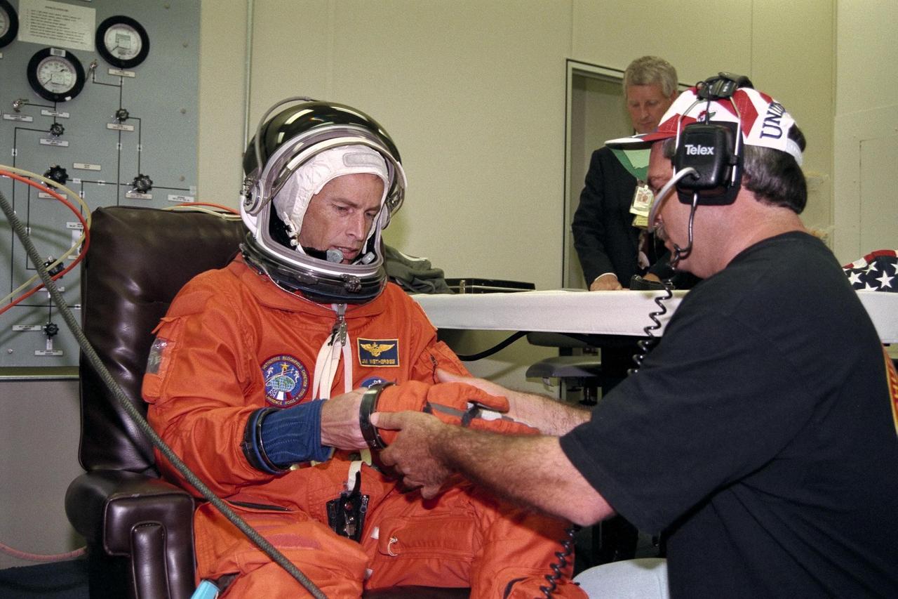STS-86 Commander James D. Wetherbee gets help from a suit technician while donning the gloves of his launch and entry suit in the Operations and Checkout Building. This will be Wetherbee’s fourth spaceflight. He and the six other crew members will depart shortly for Launch Pad 39A, where the Space Shuttle Atlantis awaits liftoff on a 10-day mission slated to be the seventh docking of the Space Shuttle with the Russian Space Station Mir