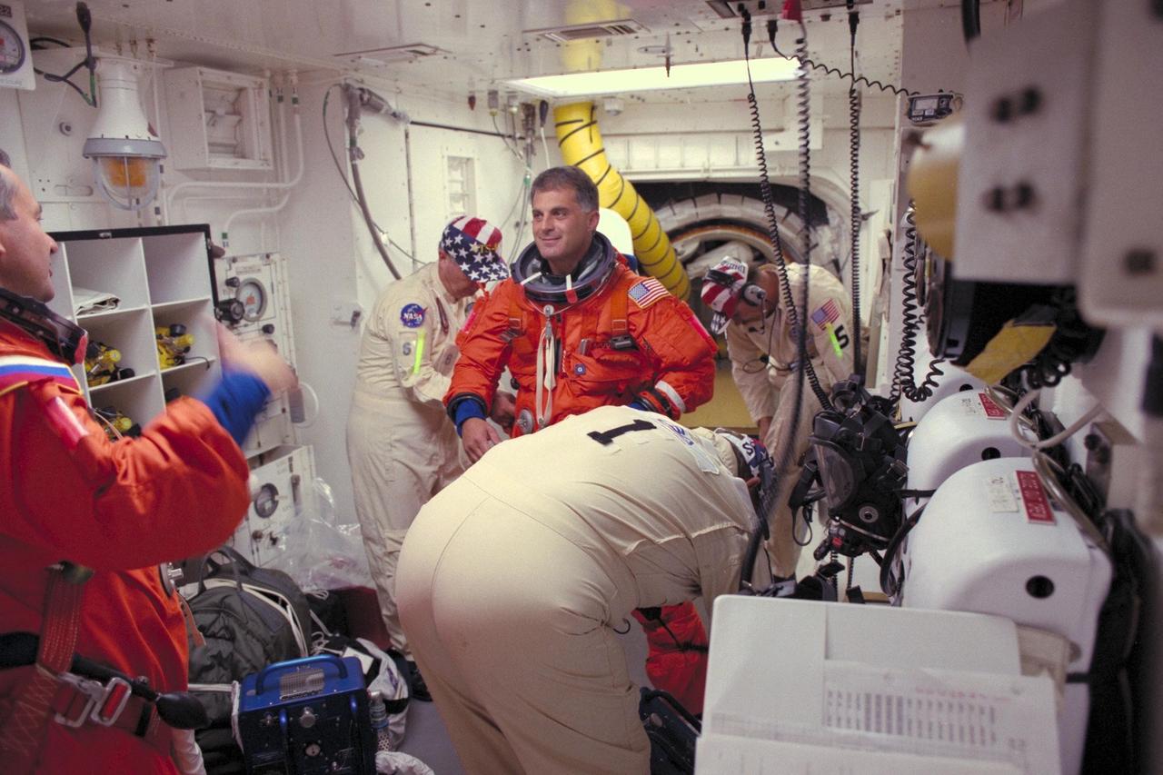STS-86 Mission Specialist David A. Wolf, at center facing camera, prepares to enter the Space Shuttle Atlantis at Launch Pad 39A, with the assistance of Rick Welty, in foreground at center, United Space Alliance (USA) orbiter vehicle closeout chief; and closeout team members, in background from left, Jim Davis, NASA quality assurance specialist; and George Schramm, USA mechanical technician. STS-86 Mission Specialist Vladimir Georgievich Titov, in foreground at far left, is awaiting his turn