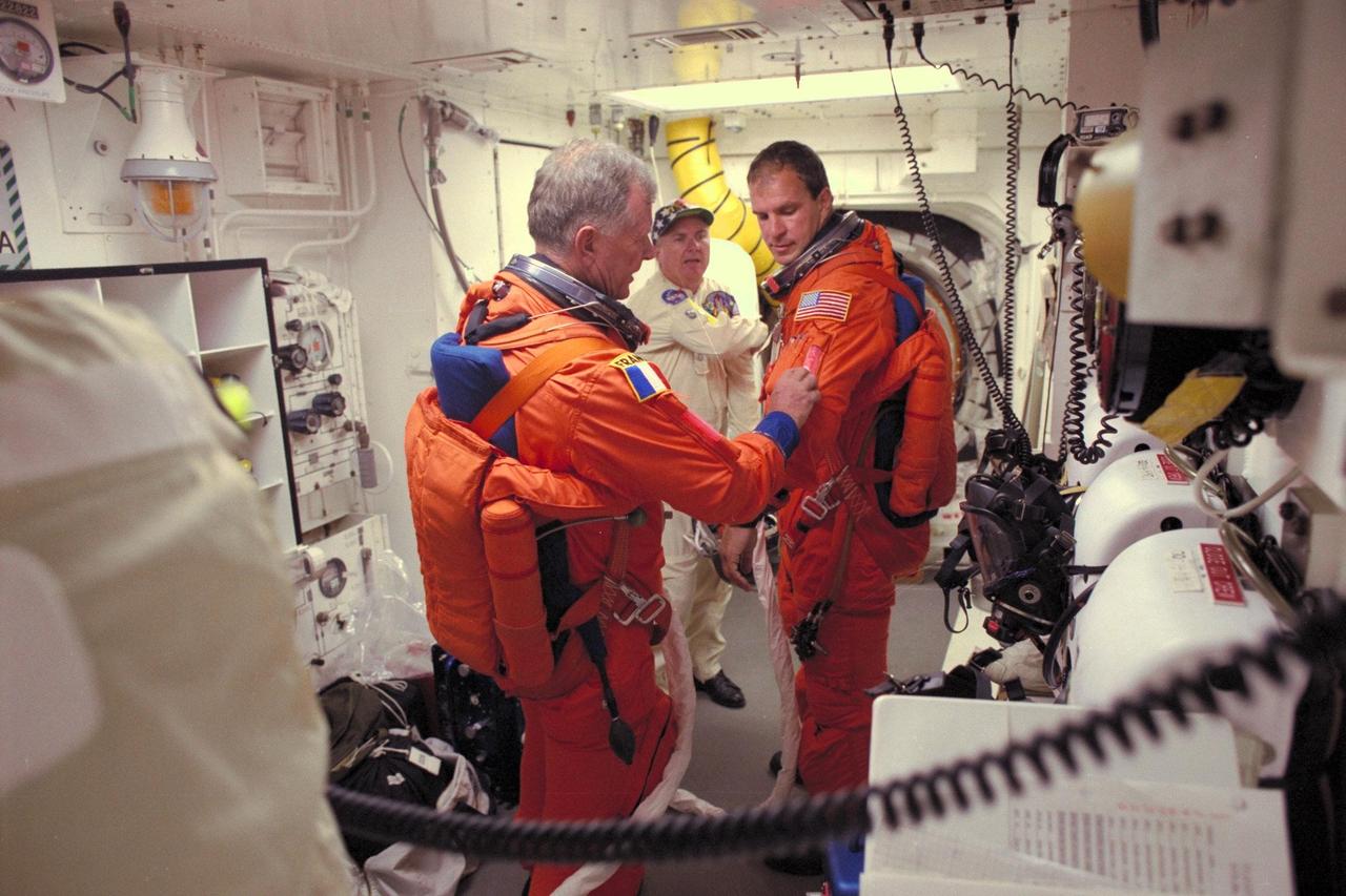 While a white room closeout crew member looks on, STS-86 Pilot Michael J. Bloomfield, at right, gets some assistance from fellow crew member, Mission Specialist Jean-Loup J.M. Chretien of the French Space Agency, CNES, before entering the Space Shuttle Atlantis at Launch Pad 39A
