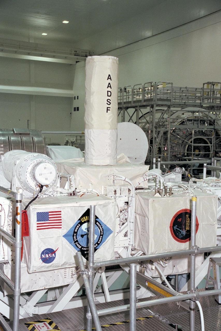 United States Microgravity Payload-4 (USMP-4) experiments are prepared to be flown on Space Shuttle mission STS-87 in the Space Station Processing Facility at Kennedy Space Center (KSC). The large white vertical cylinder in the center of the photo is the Advanced Automated Directional Solidification Furnace (AADSF) and the horizontal tube to the left of it is MEPHISTO, a French acronym for a cooperative American-French investigation of the fundamentals of crystal growth. Seen at right behind the AADSF in the circular white cover is the Isothermal Dendritic Growth Experiment (IDGE), which will be used to study the dendritic solidification of molten materials in the microgravity environment. Under the multi-layer insulation with the American flag and mission logo is the Space Acceleration Measurement System, or SAMS, which measures the microgravity conditions in which the experiments are conducted. All of these experiments are scheduled for launch aboard STS-87 on Nov. 19 from KSC