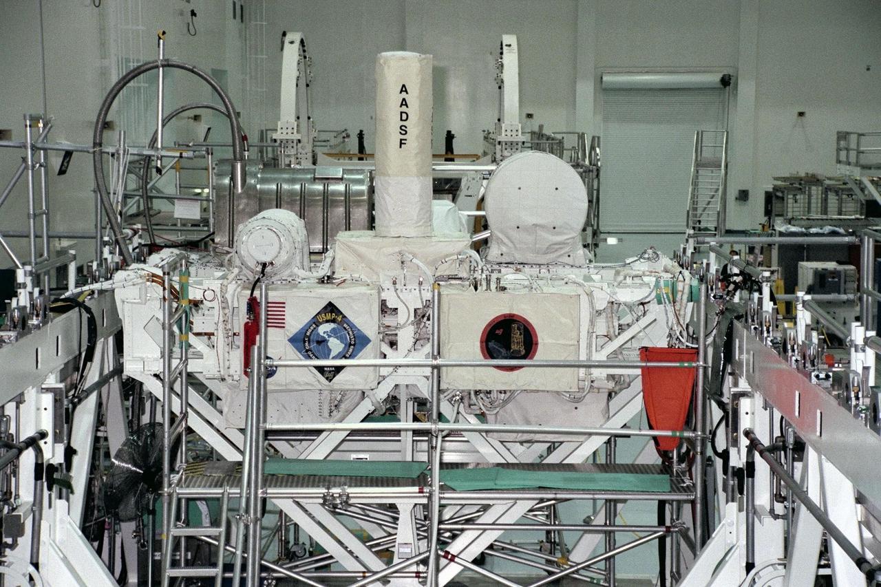 United States Microgravity Payload-4 (USMP-4) experiments are prepared to be flown on Space Shuttle mission STS-87 in the Space Station Processing Facility at Kennedy Space Center (KSC). Seen in the foreground at right is the USMP-4 logo with the acronyms of its experiments. Above the American flag at left is the MEPHISTO experiment, a cooperative American and French investigation of the fundamentals of crystal growth. Scientists will study changes in solidification rates, temperature, and interface shape of an alloy to understand how these changes affect composition and properties of the metal produced. Under the multi-layer insulation with the American flag and mission logo is the Space Acceleration Measurement System, or SAMS, which measures the microgravity conditions in which the experiments are conducted. All USMP-4 experiments are scheduled for launch aboard STS-87 on Nov. 19 from KSC