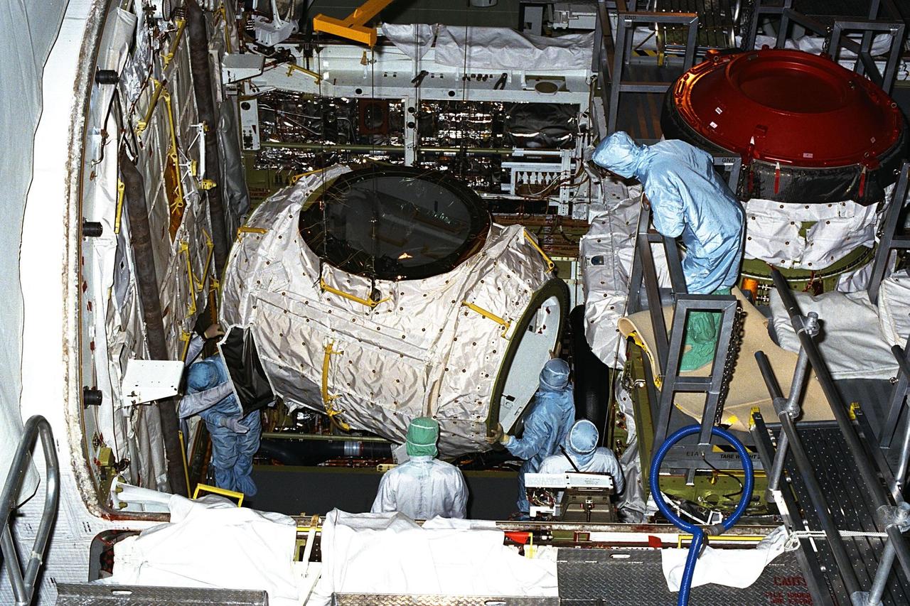 The tunnel adapter (left) which will be flown on the STS-89 mission is being installed in the Space Shuttle orbiter Endeavour's payload bay in Orbiter Processing Facility bay 1. To the right is the Orbiter Docking System (ODS), with its distinctive red Russian-built Androgynous Peripheral Docking System (APDS). STS-89 will be the eighth U.S. docking mission with the Russian Mir space station. The nine-day space flight is scheduled for launch in mid-January 1998